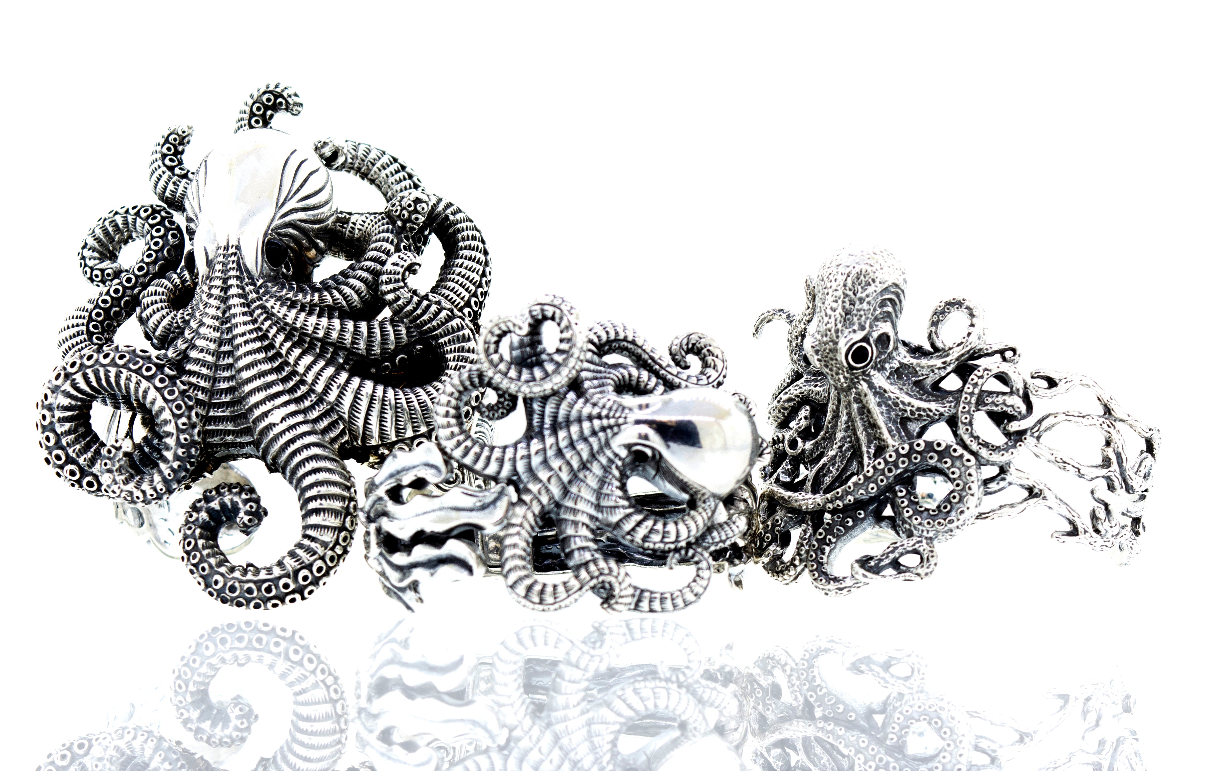 Intricate silver octopus sculptures with detailed tentacles and textures on a white background.