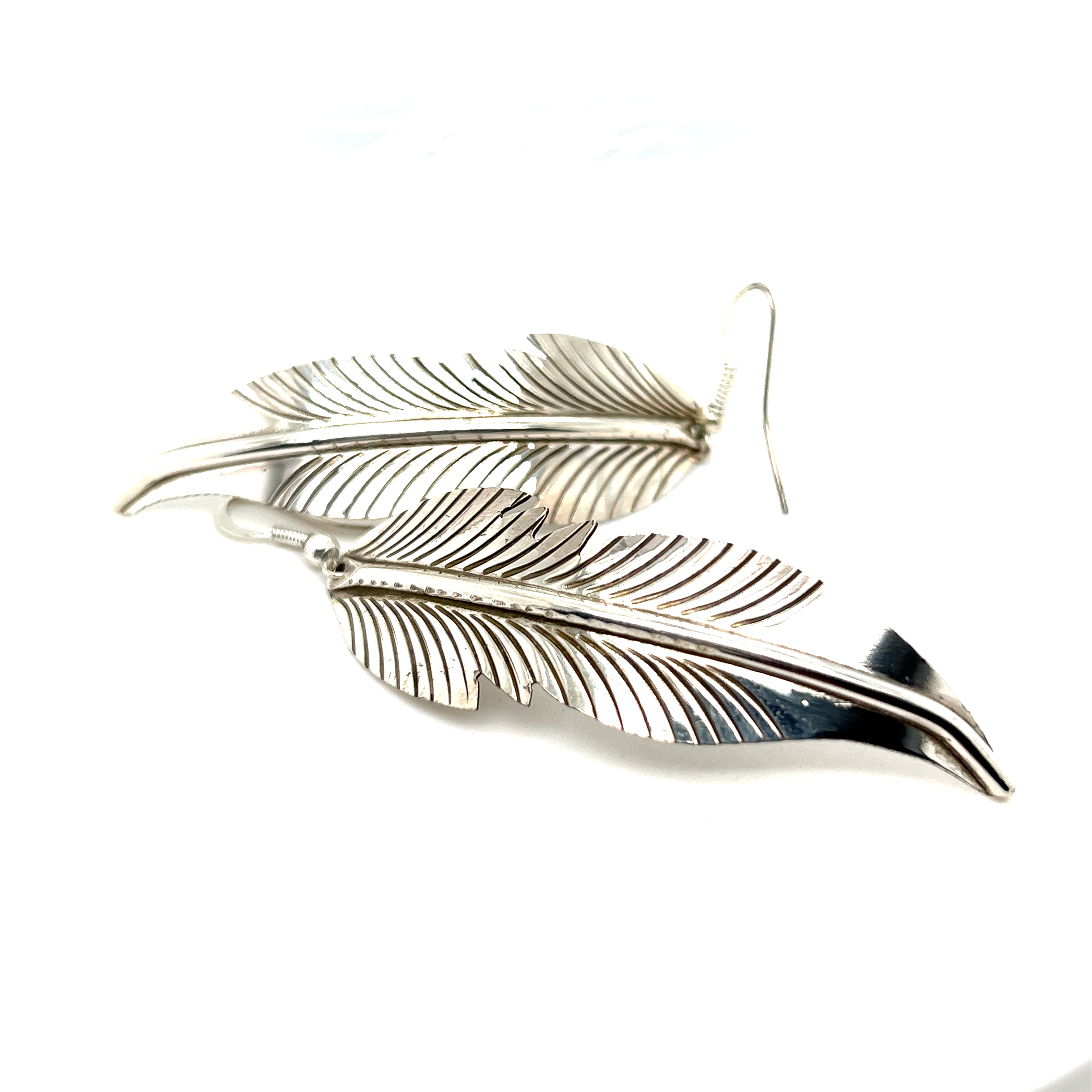 A pair of Super Silver Striking Native American Feather Earrings on a white surface.
