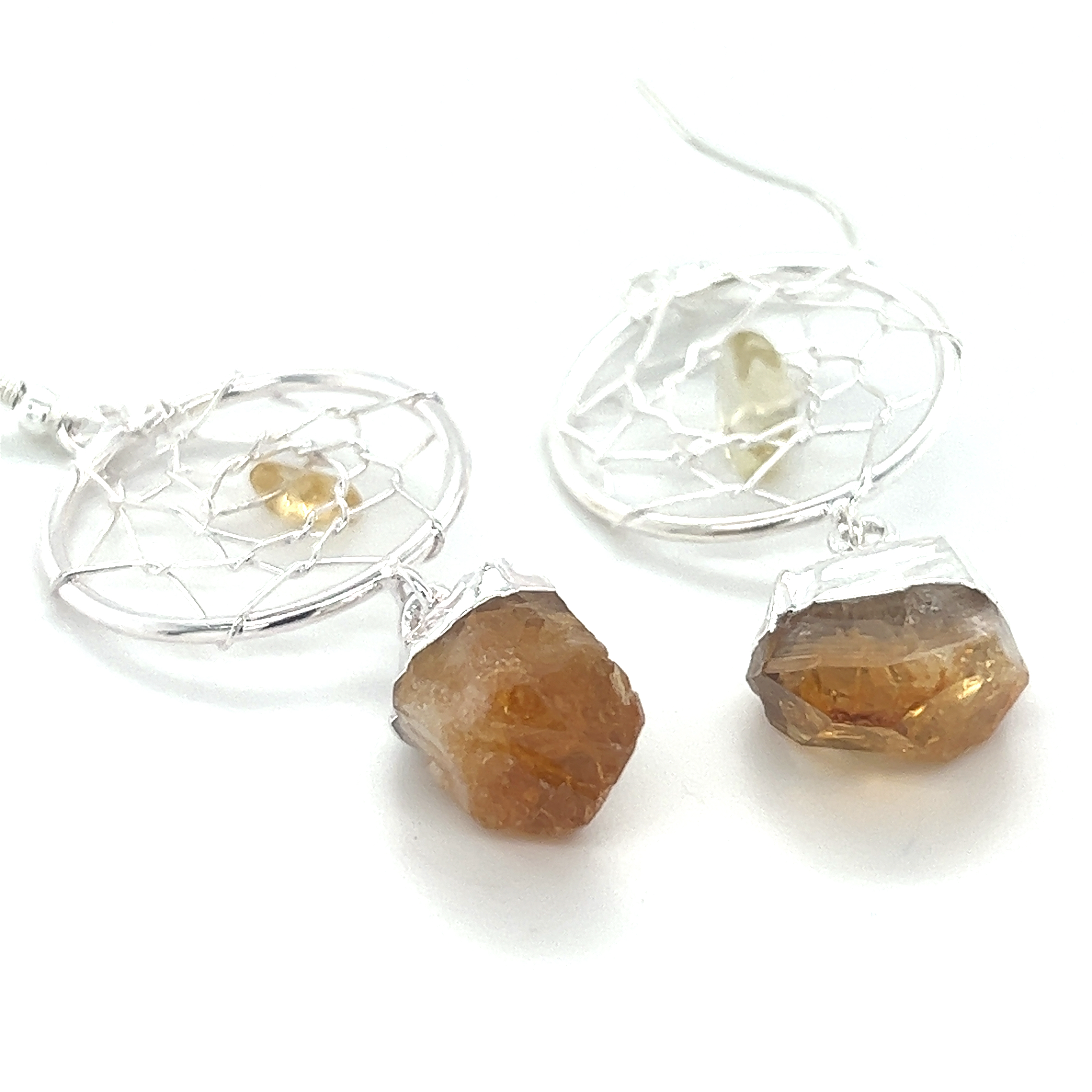 A pair of Raw Crystal Dream Catcher Earrings from Super Silver with a yellow gemstone and a silver wire.