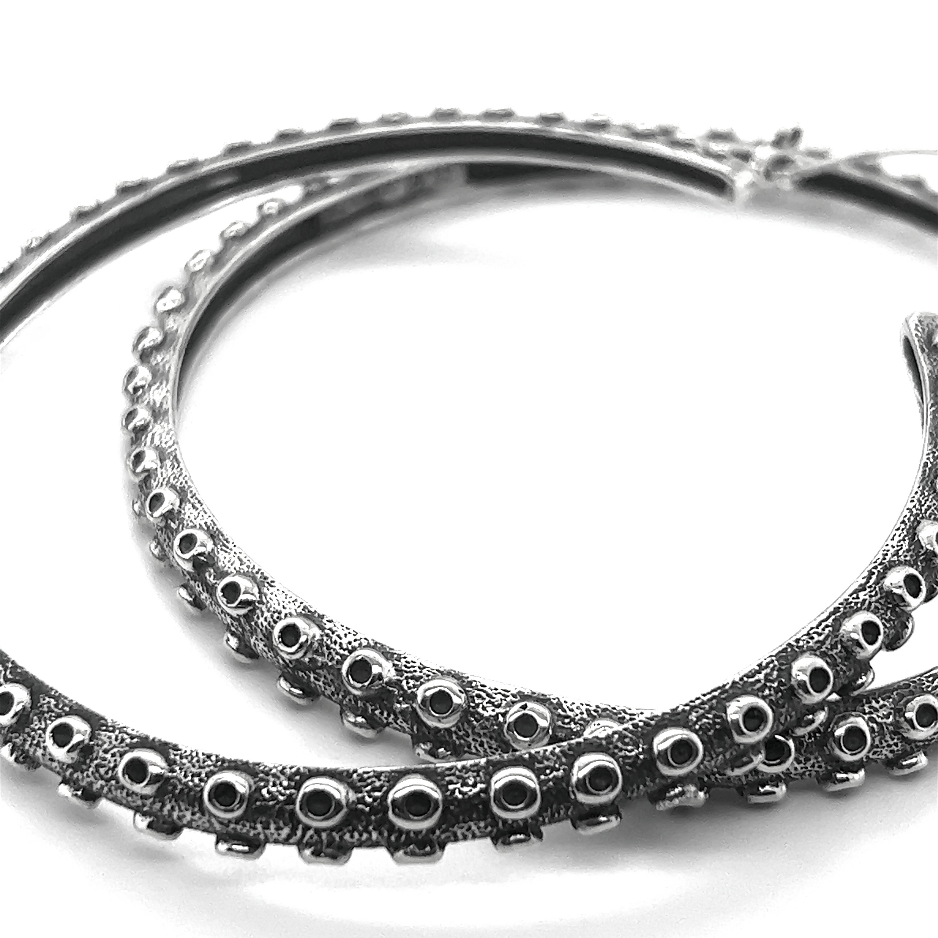 A mesmerizing pair of Colossal Tentacle Hoop earrings by Super Silver on a white background.