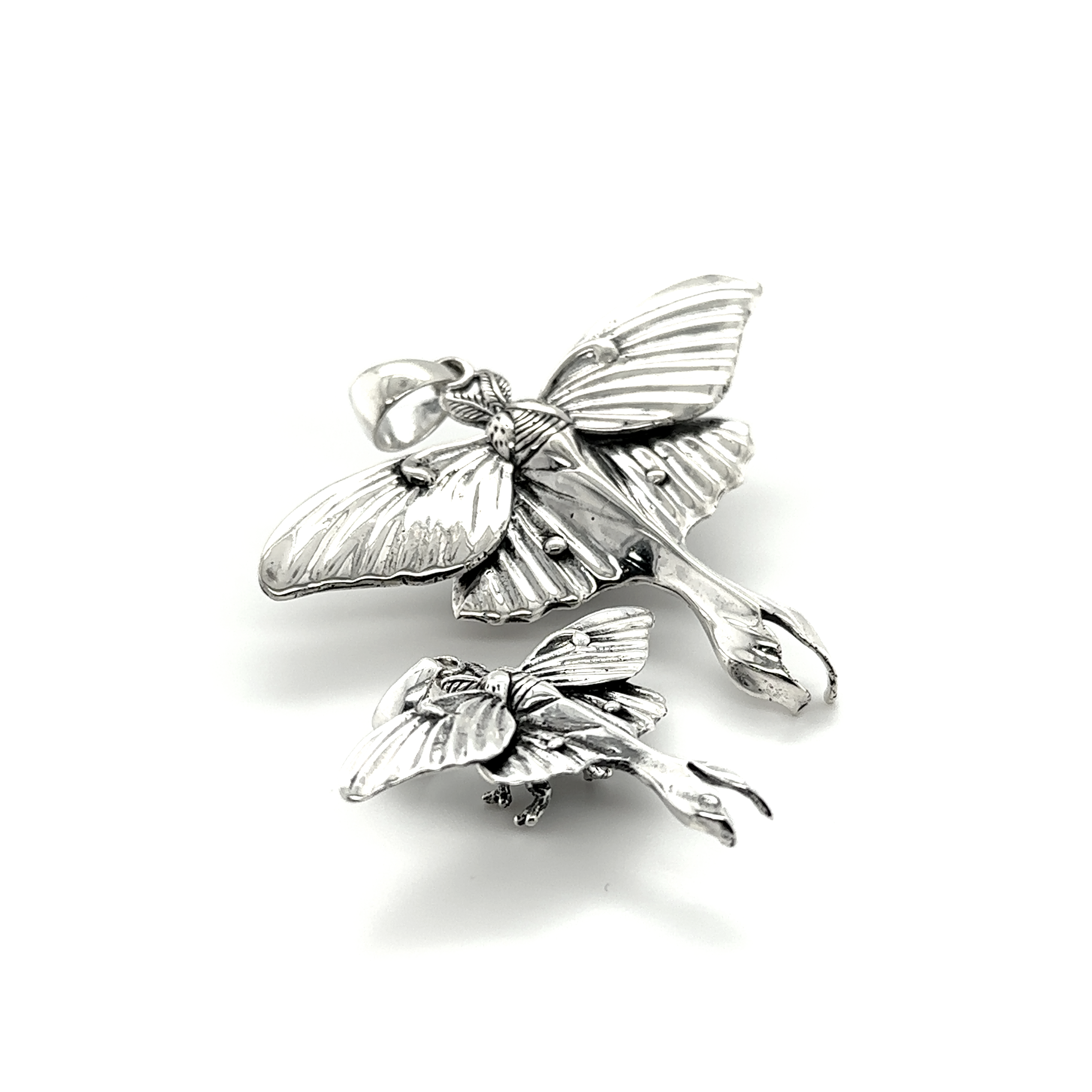 A pair of Statement Lunar Moth Pendants, radiating ethereal beauty and symbolizing transformation, delicately rest on a pristine white surface.