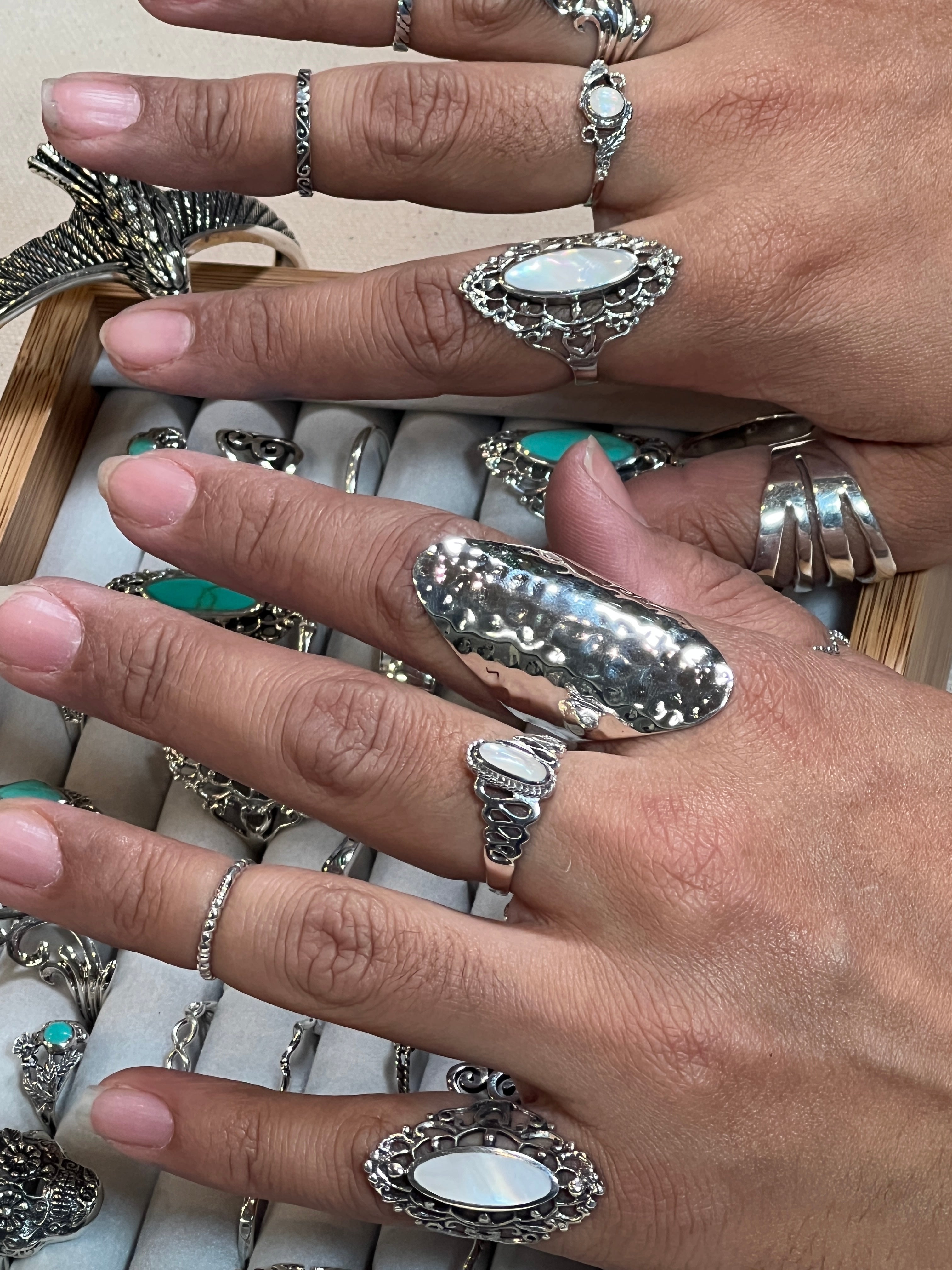 A woman's hands adorned with Super Silver's Statement Hammered Rings, including a silver hammered ring, delicately placed in a box.