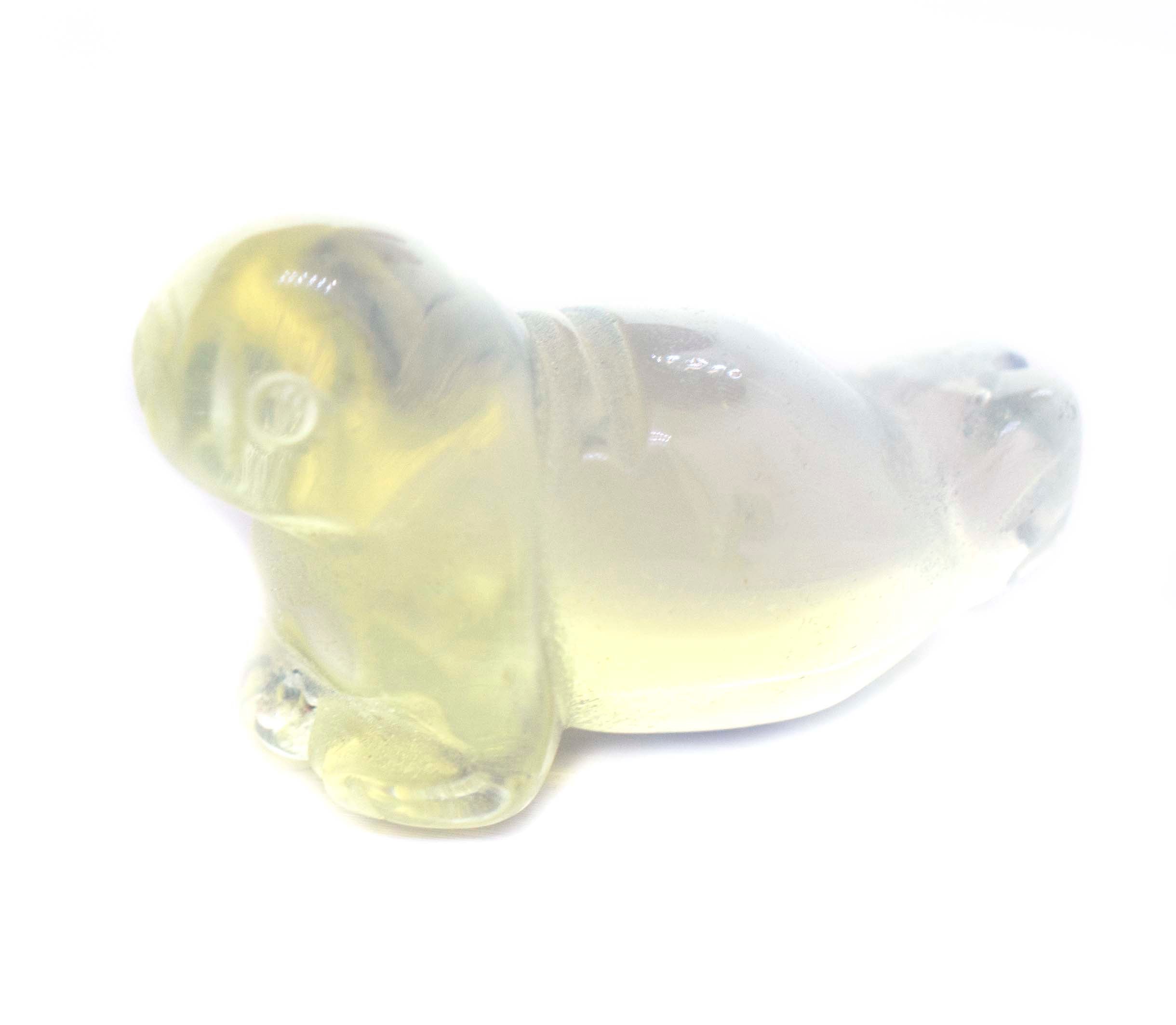 A Carved Opalite Seal Figure sitting on a white surface, capturing the playful essence of the ocean.