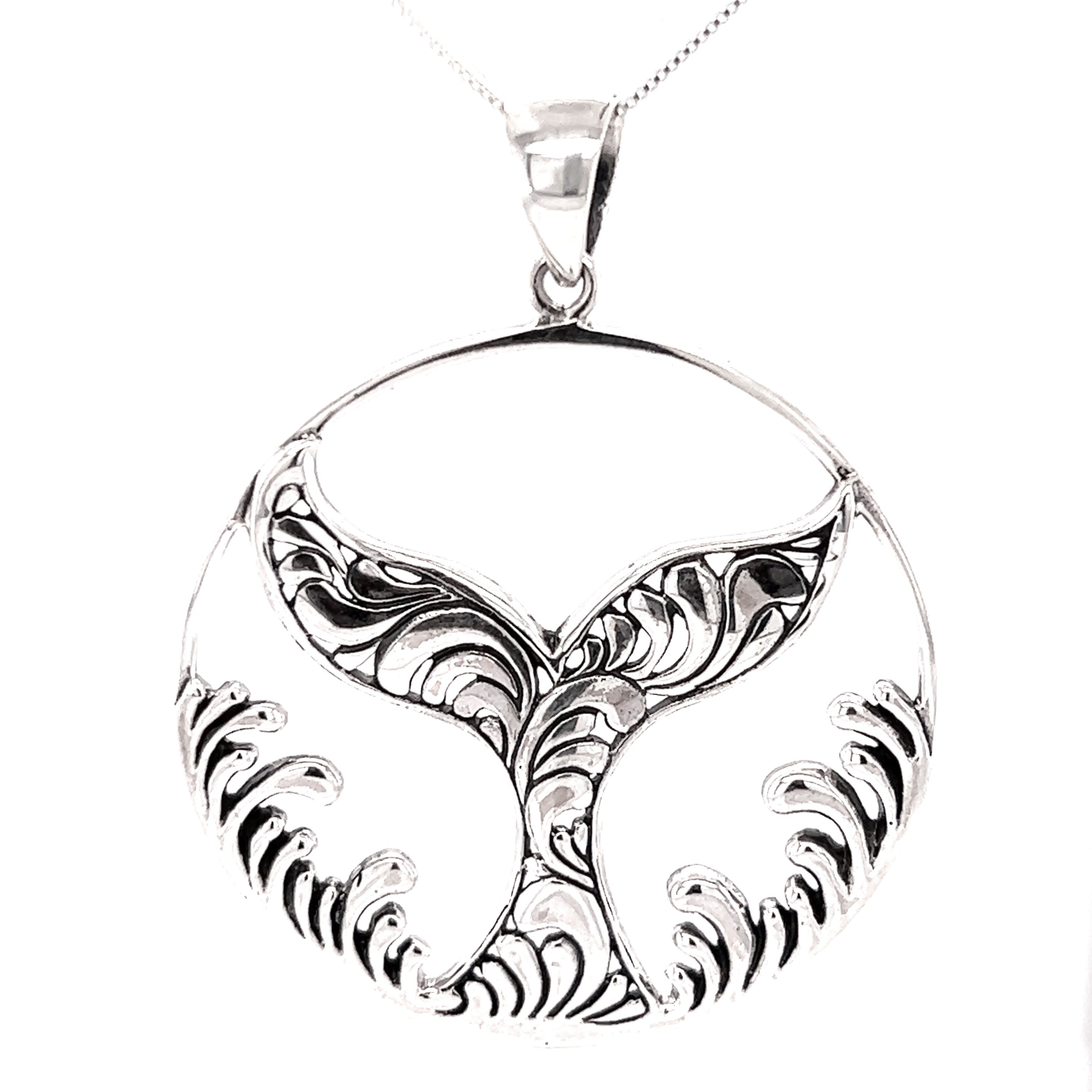 A handcrafted Magnificent Whale Tail Pendant with Waves, exuding a beachy charm as it hangs on a silver chain.