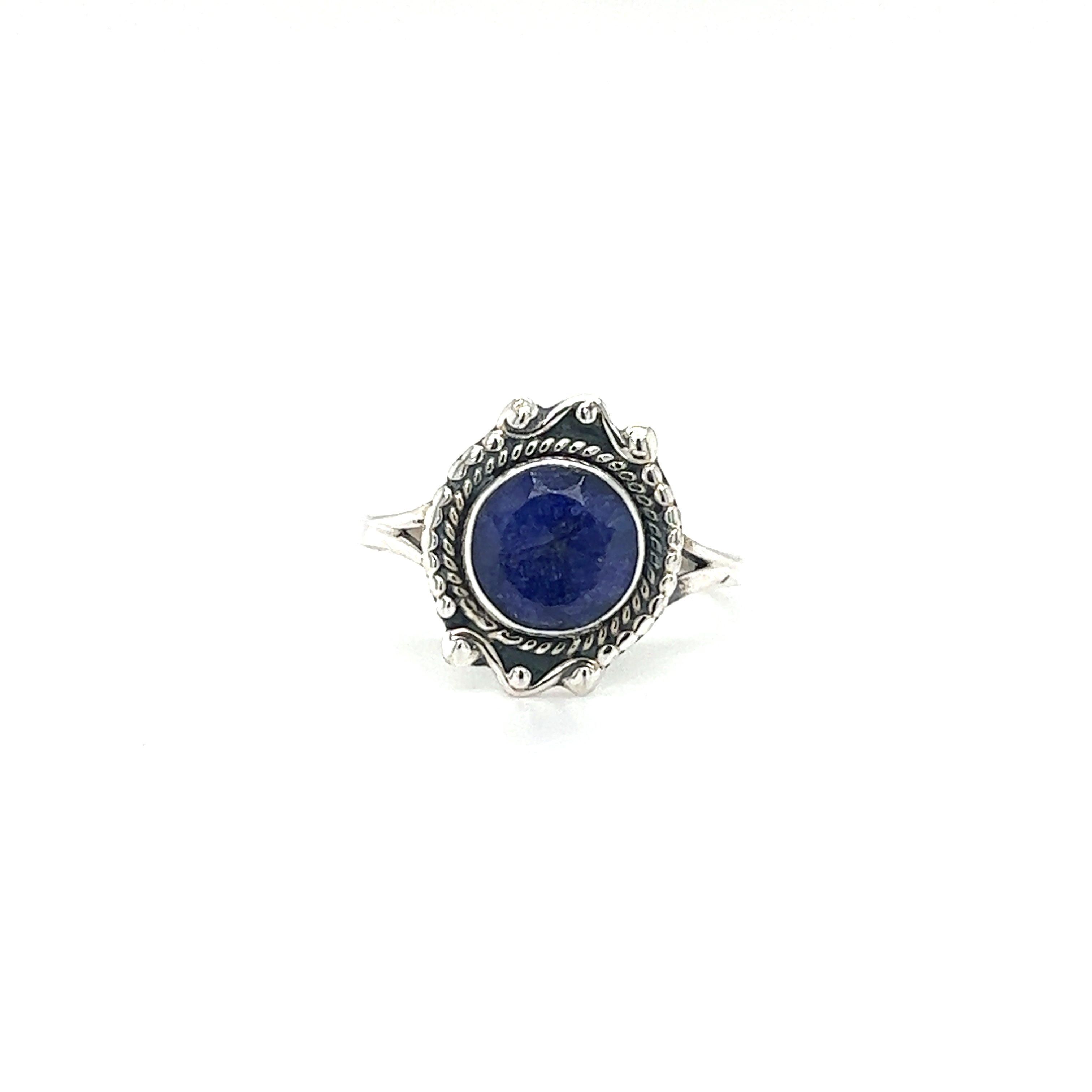 A Round Gemstone Ring With Vintage Setting with intricate details, this piece features a round blue gemstone in the center. Crafted from .925 Sterling Silver, it exudes bohemian sophistication, set elegantly against a white background.