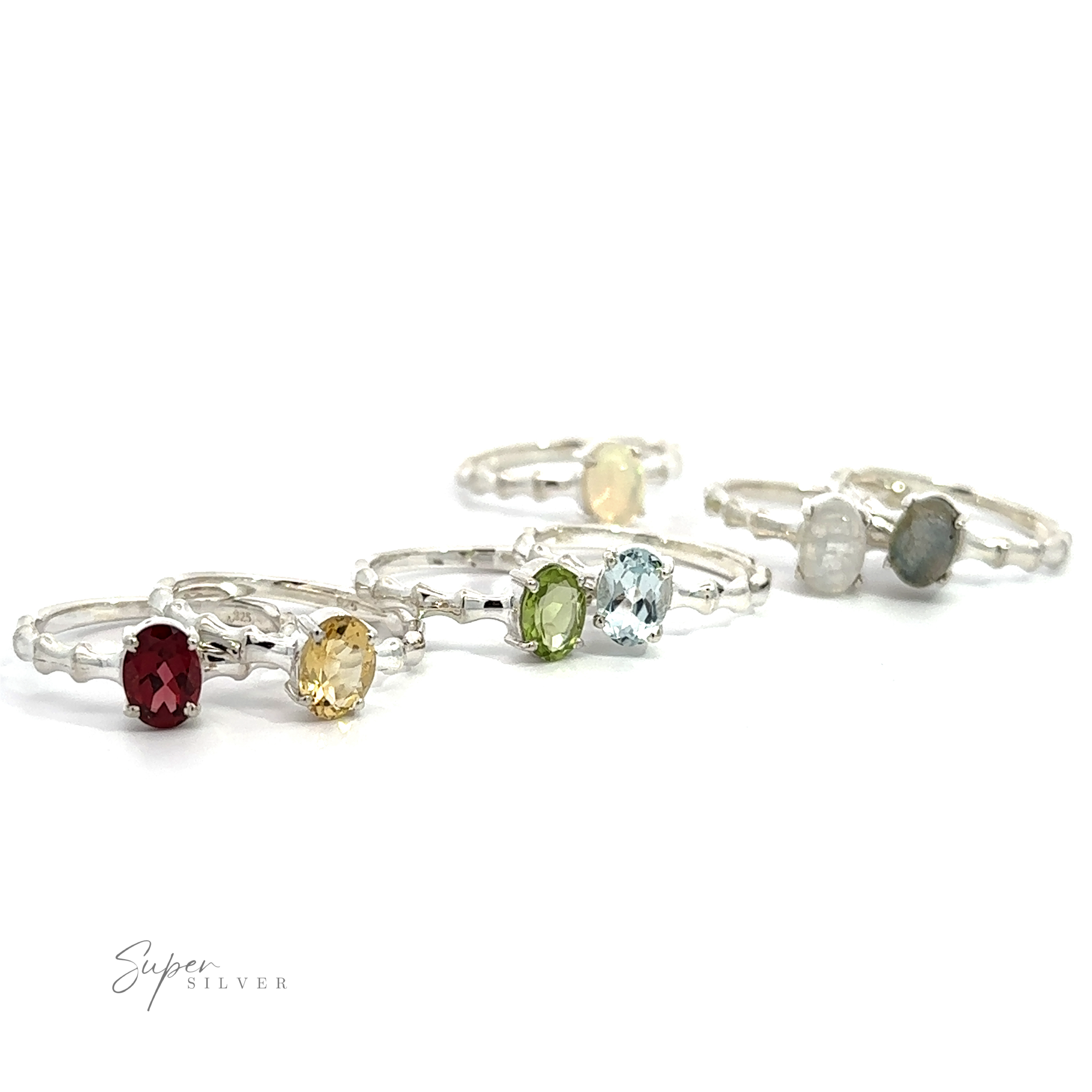 A collection of Pronged Oval Gemstone Rings with sparkling blue topaz and various colored gemstones on a white background.