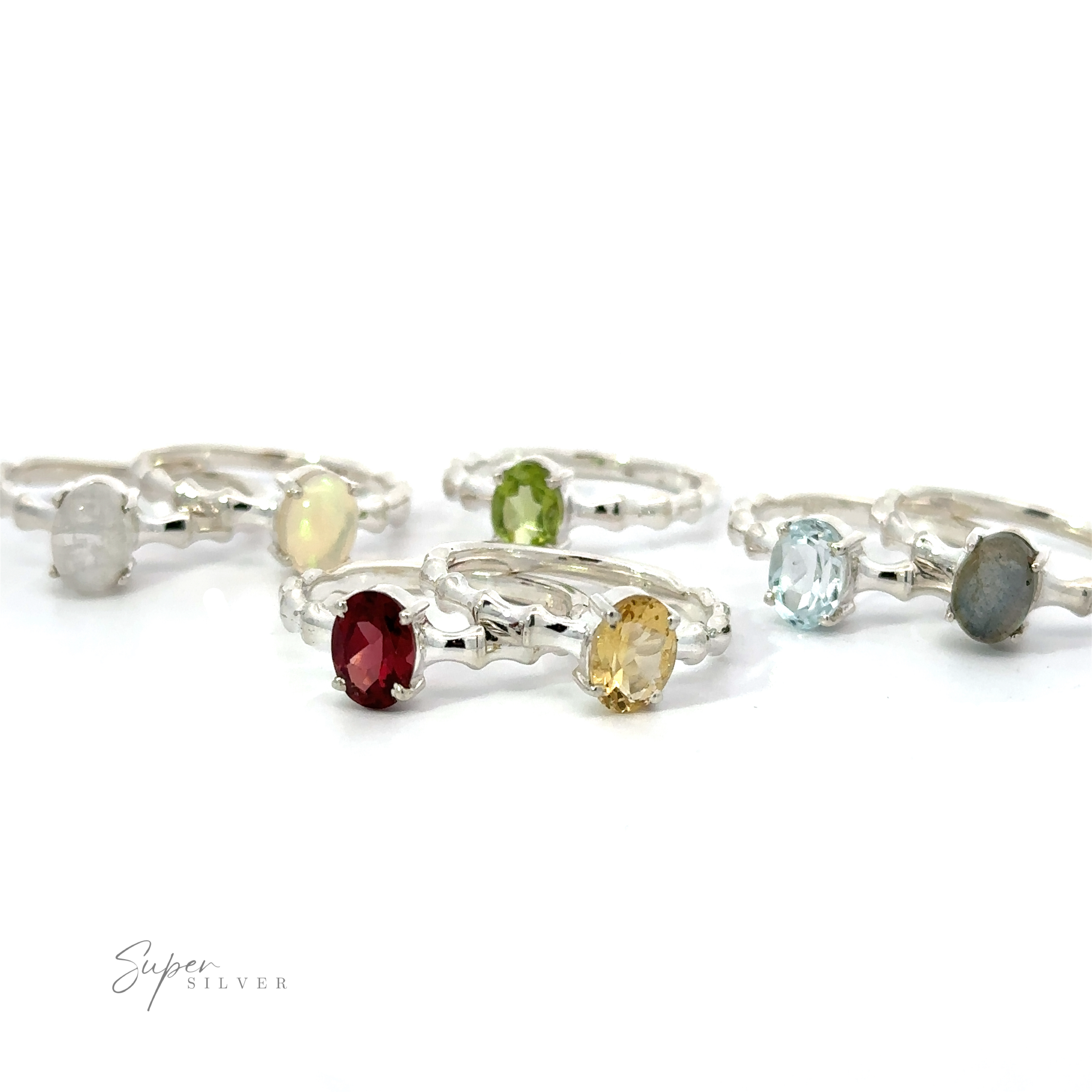 A collection of Pronged Oval Gemstone Rings with Textured Bands and various colored sparkling gemstones on a white background.