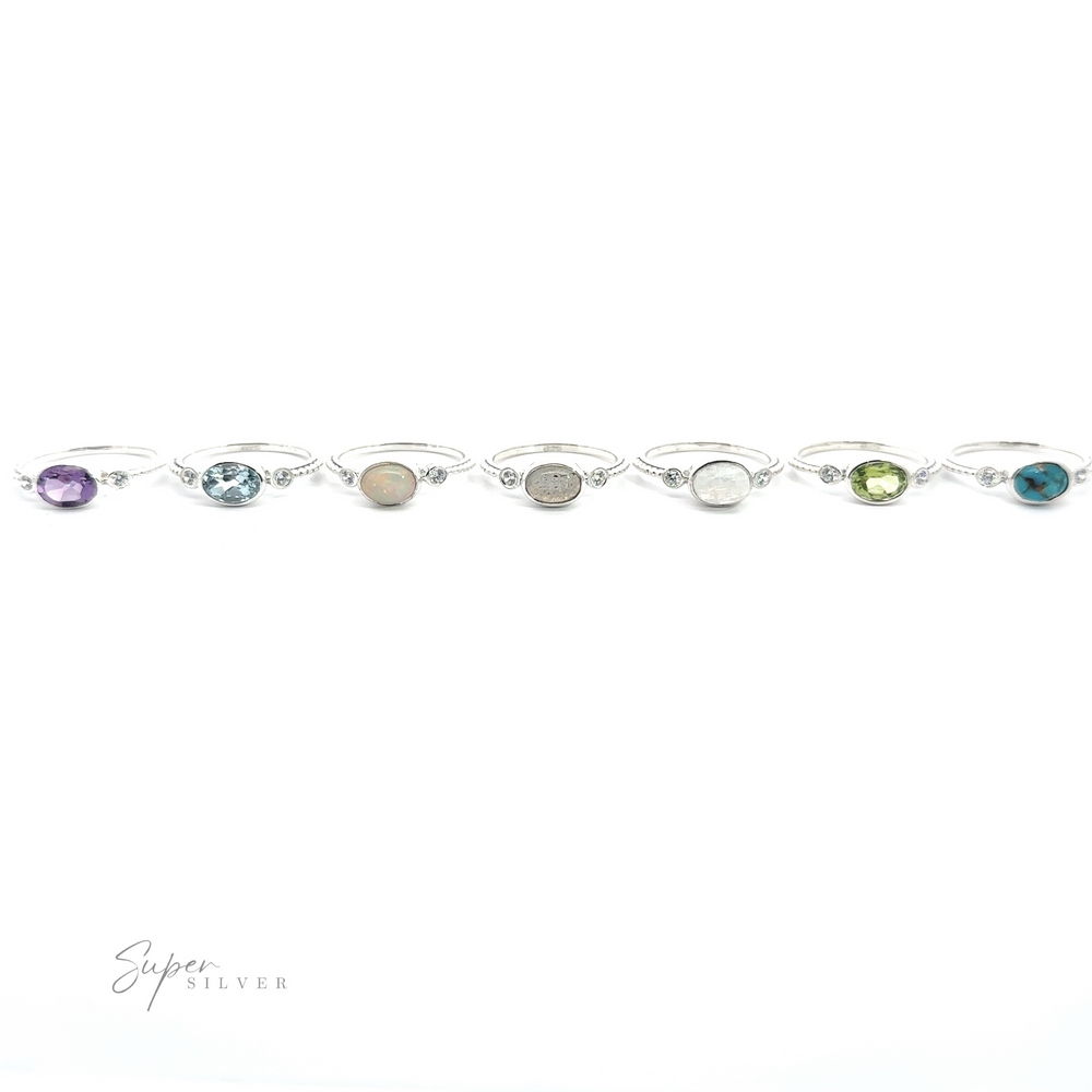 A Horizontal Oval Gemstone Ring with Beaded Band featuring multicolored gemstones, arranged on a clean, white background.
