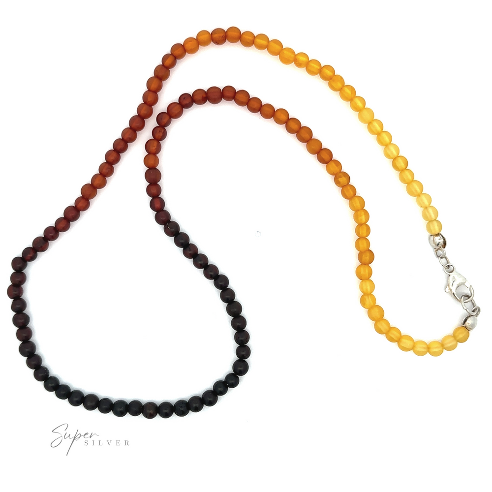 An Ombre Beaded Amber Necklace with a lobster clasp, transitioning in color from dark brown to yellow, offers a stunning addition to any sterling silver jewelry collection.