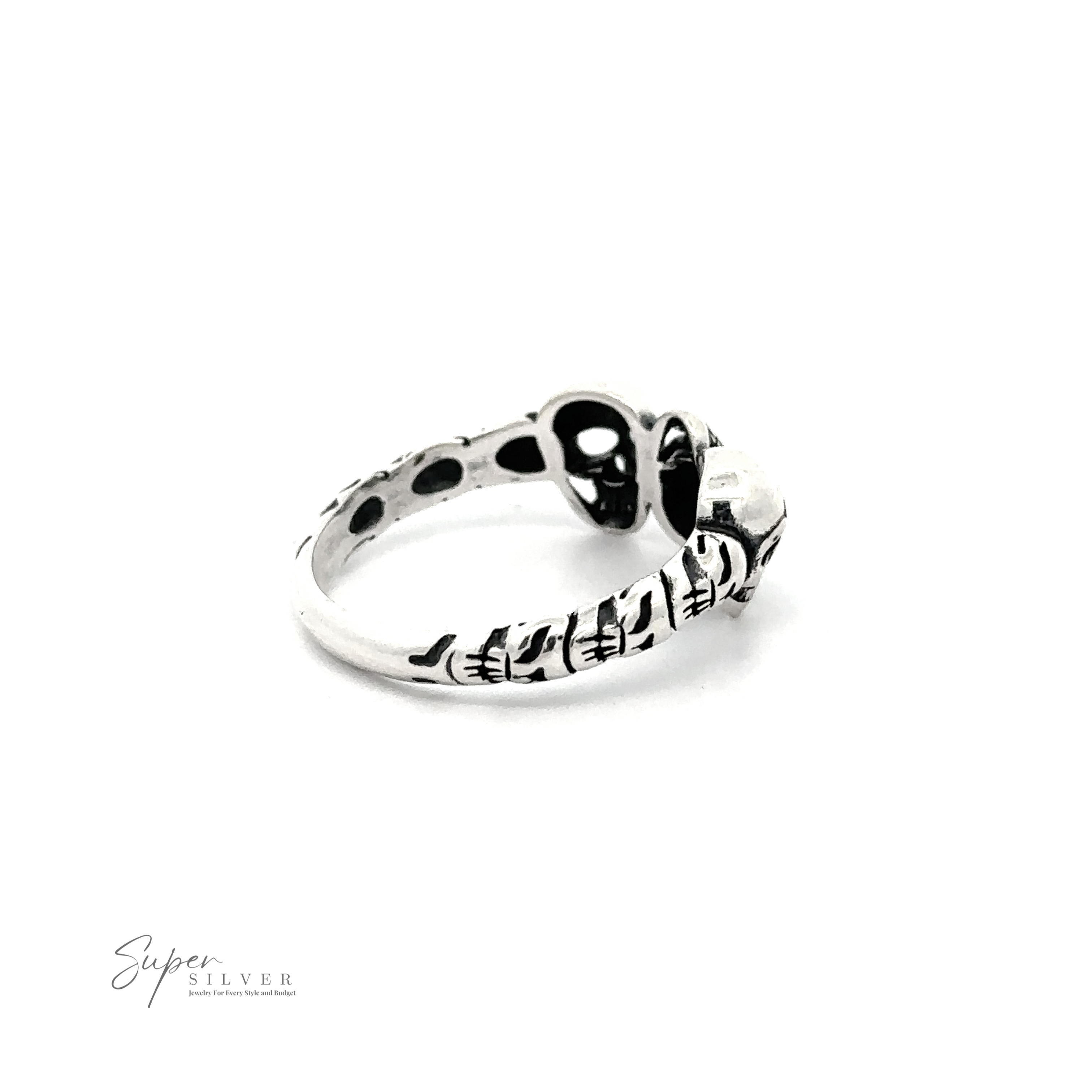 Three Skulls Ring with black skull design and engraved patterns against a white background.