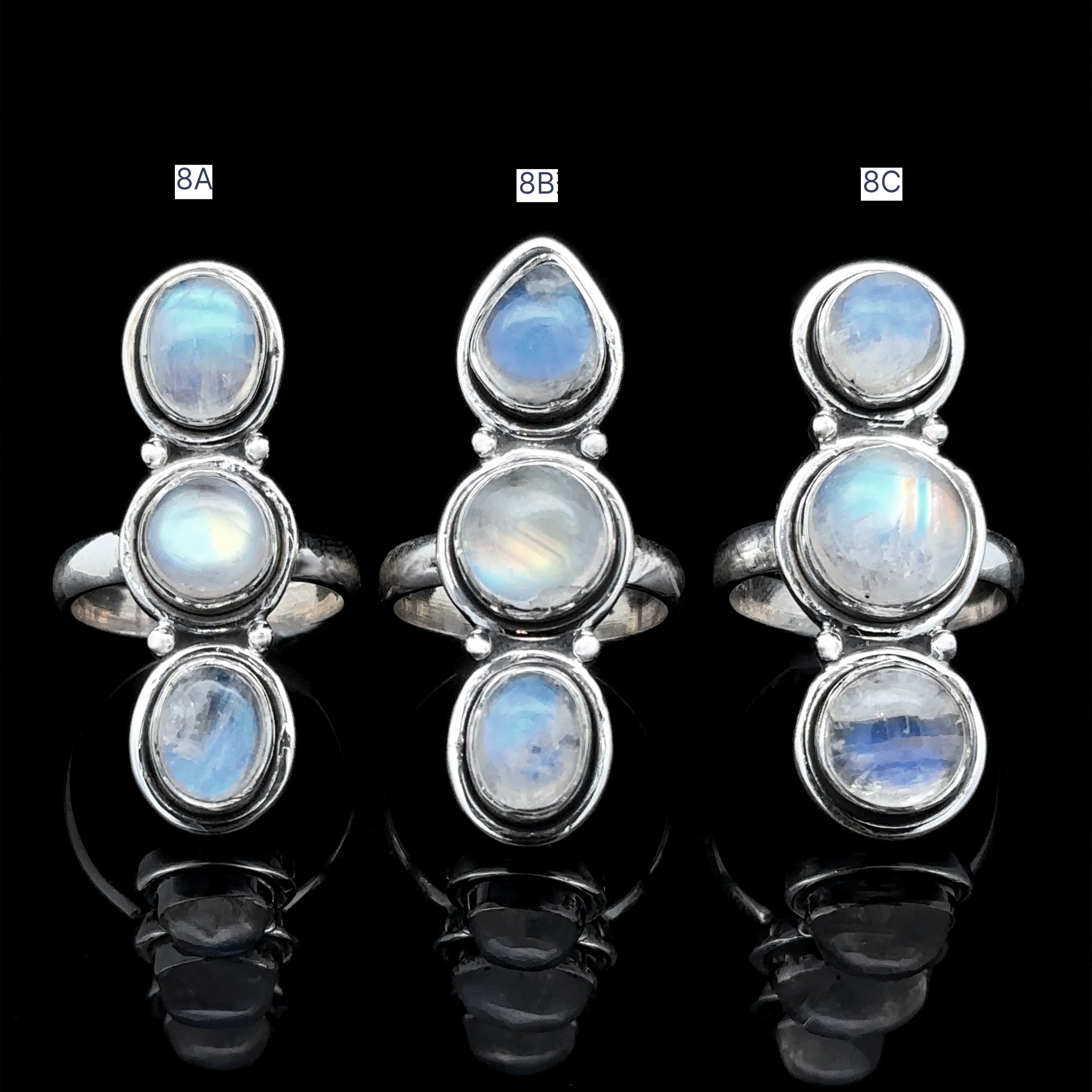Set against a black backdrop, the Triple Moonstone Rings in sterling silver, labeled 8A, 8B, and 8C, are adorned with enchanting moonstones. Each ring is crafted to channel goddess energy and possesses an enduring charm.