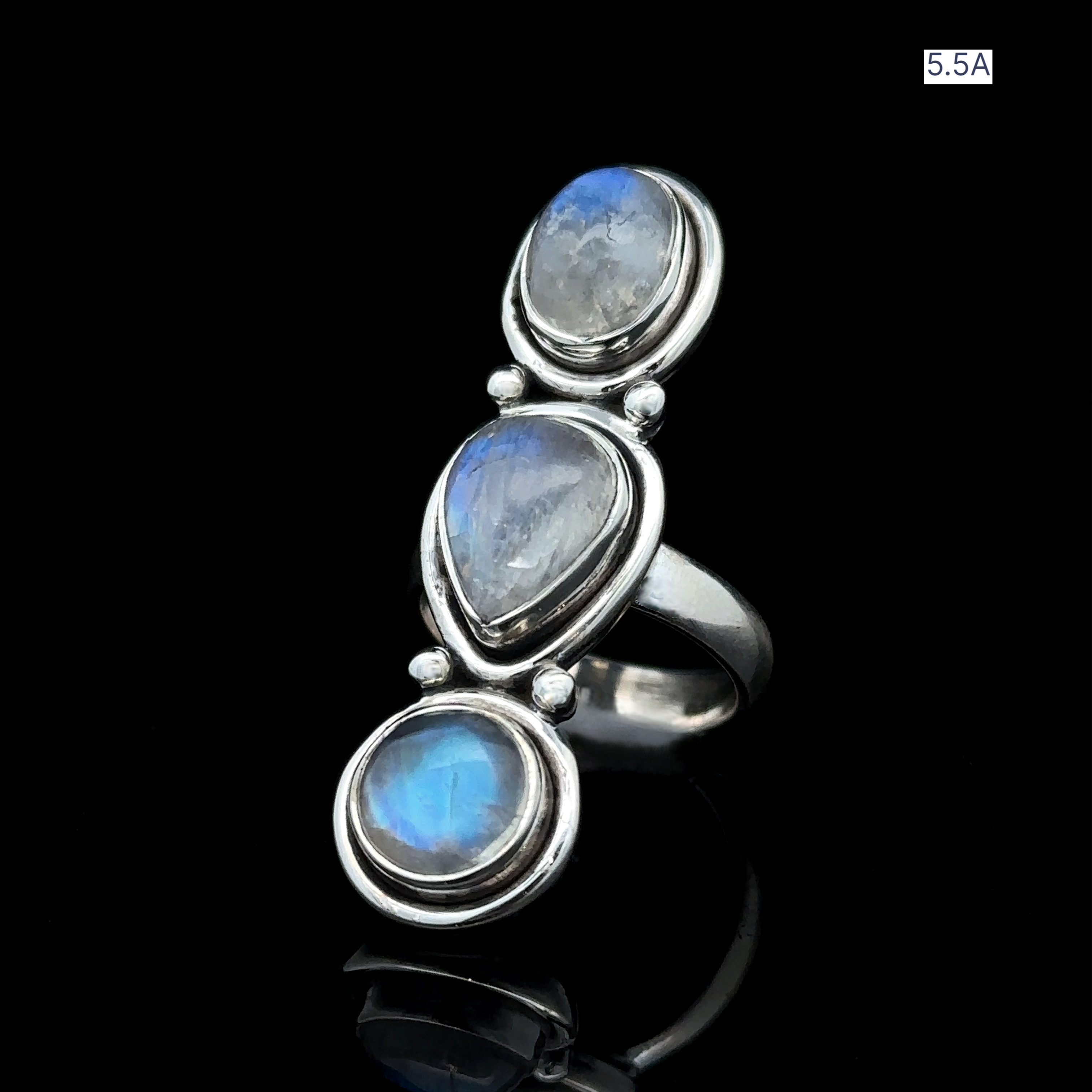 The Triple Moonstone Ring, crafted from sterling silver and featuring three oval moonstones set against a black background, is labeled "5.5A" in the top right corner. Embrace your goddess energy with this exquisite piece.