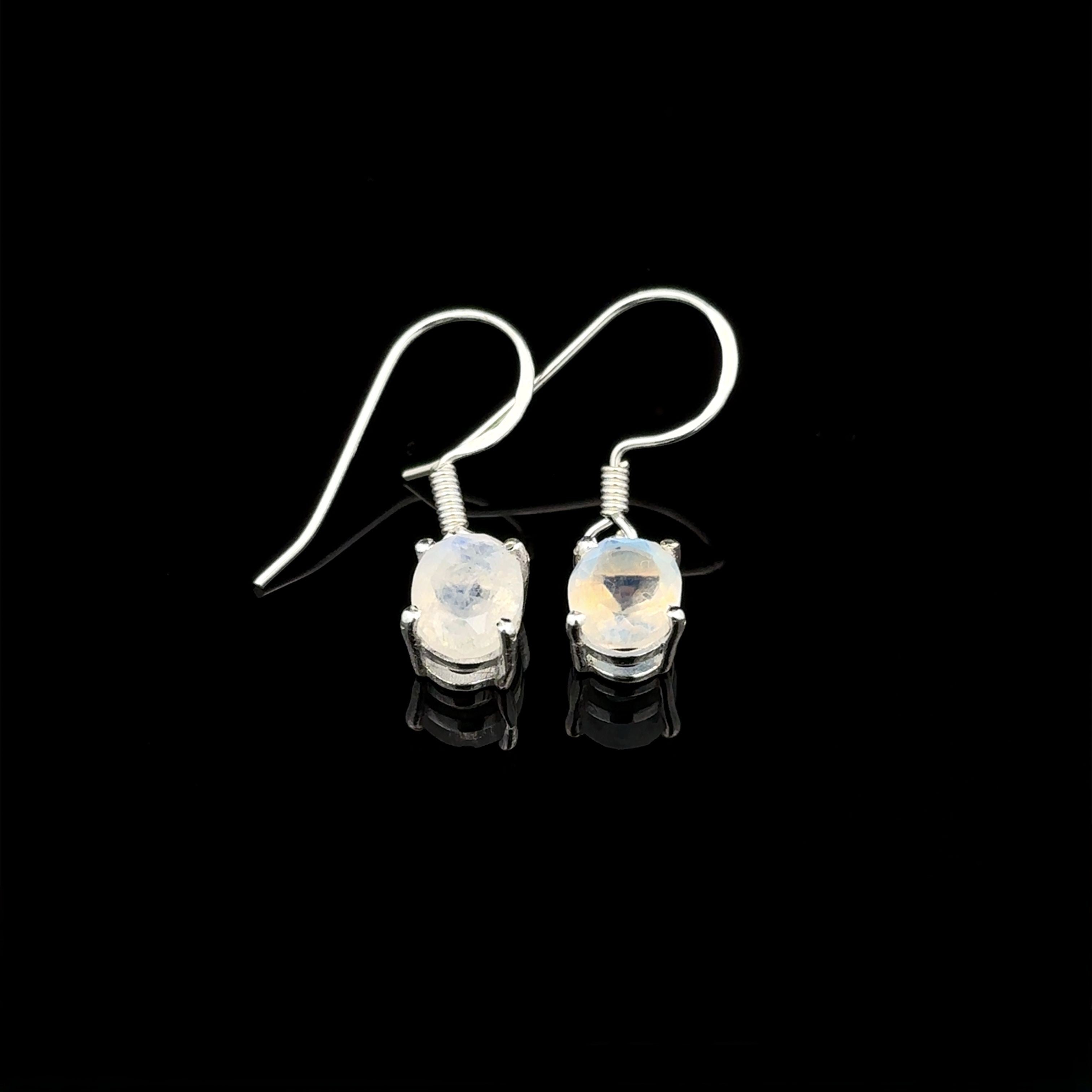 The Brilliant Oval Gemstone Earrings are sterling silver hook earrings with oval, translucent gemstones in prong settings, shown on a black background.