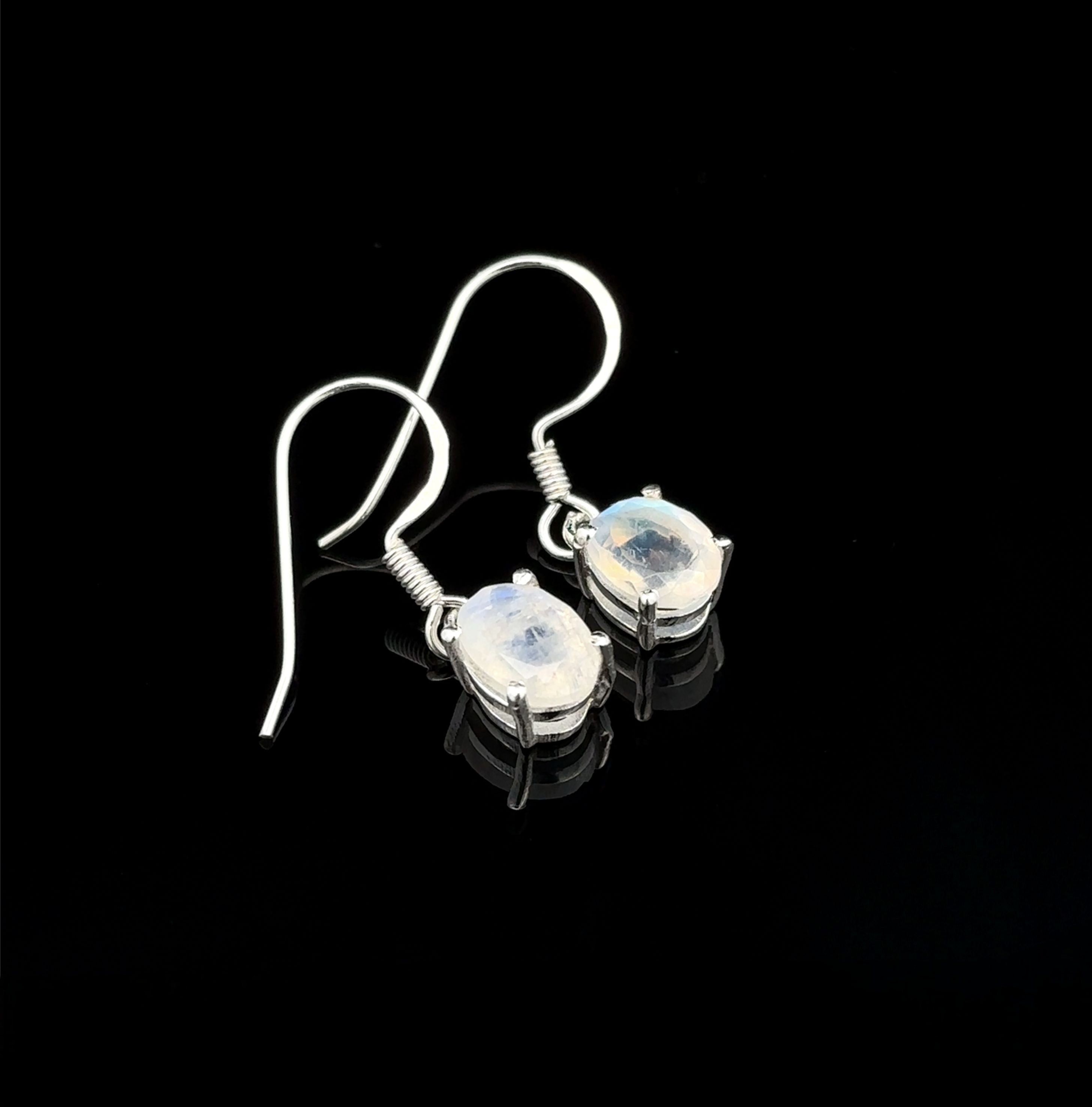 Brilliant Oval Gemstone Earrings feature sterling silver settings with oval, translucent gemstones in prongs, shown on a black background.