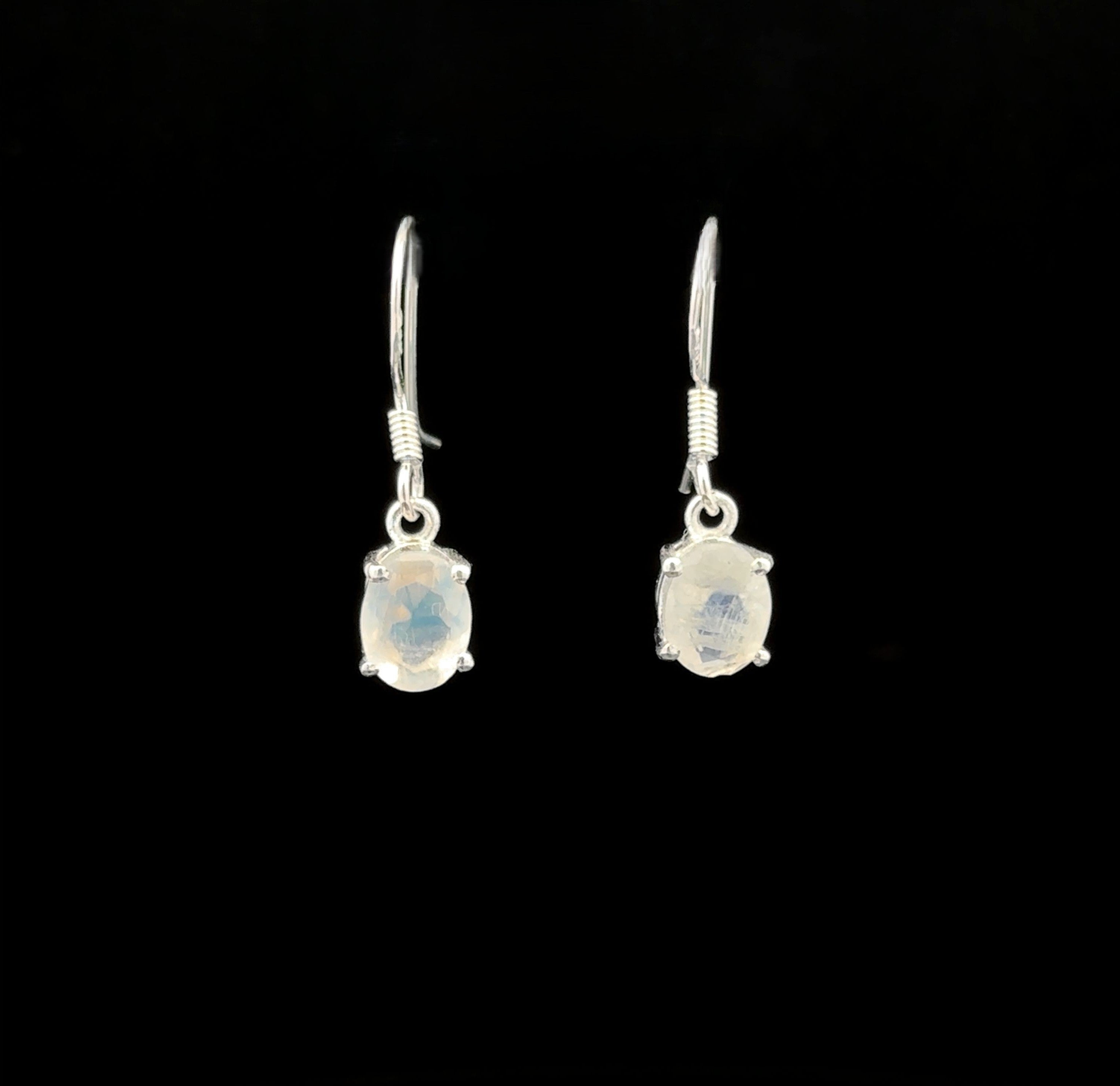 The Brilliant Oval Gemstone Earrings feature semi-transparent, oval-shaped gemstones in sterling silver four-prong settings, beautifully displayed against a black background.