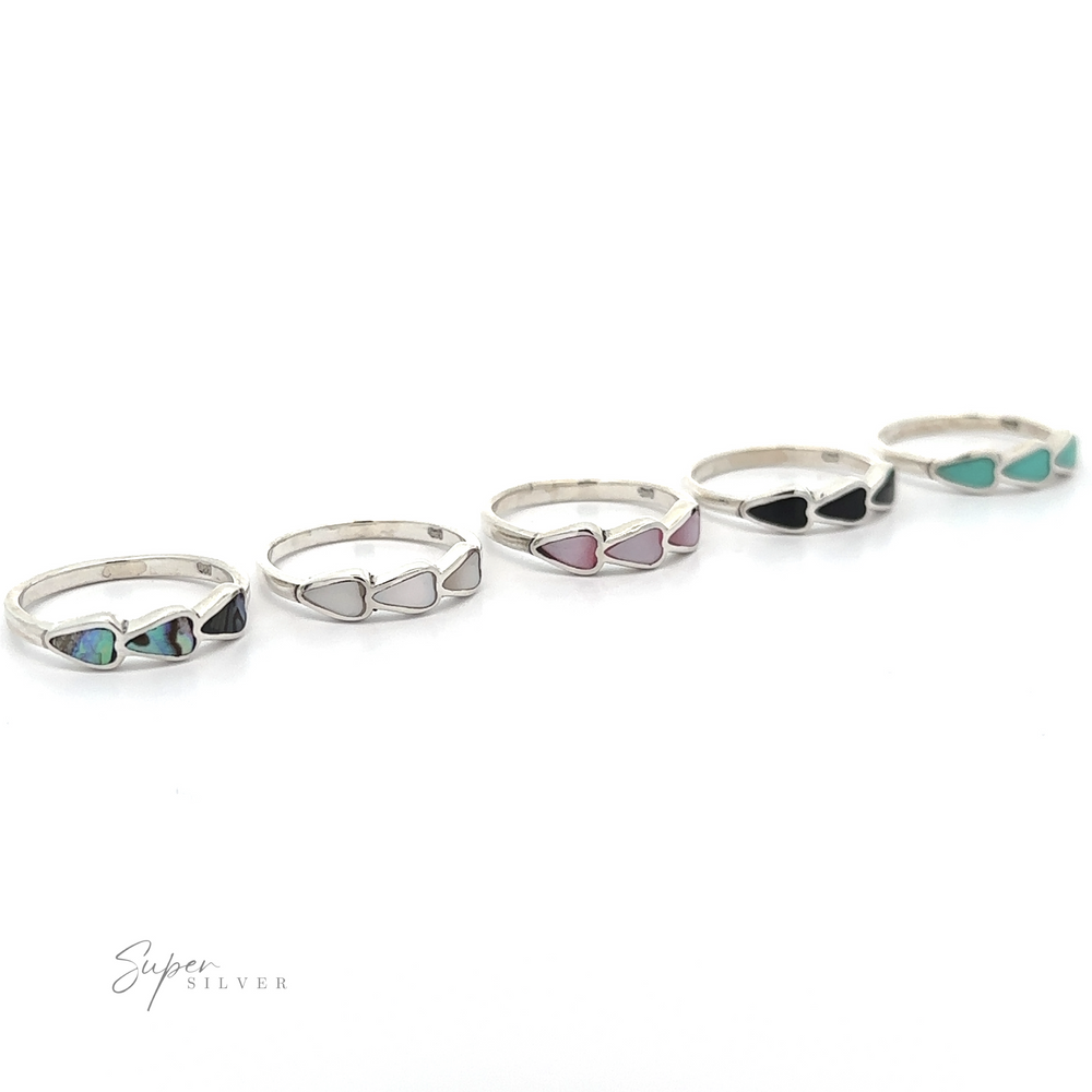 A row of Triple Heart Rings with inlaid stones, including heart-shaped stones.