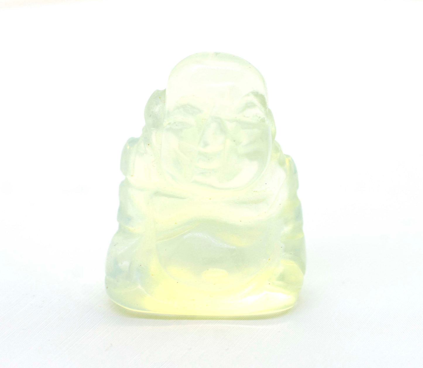 A small Laughing Buddha Gemstone Figure sitting on a white surface.