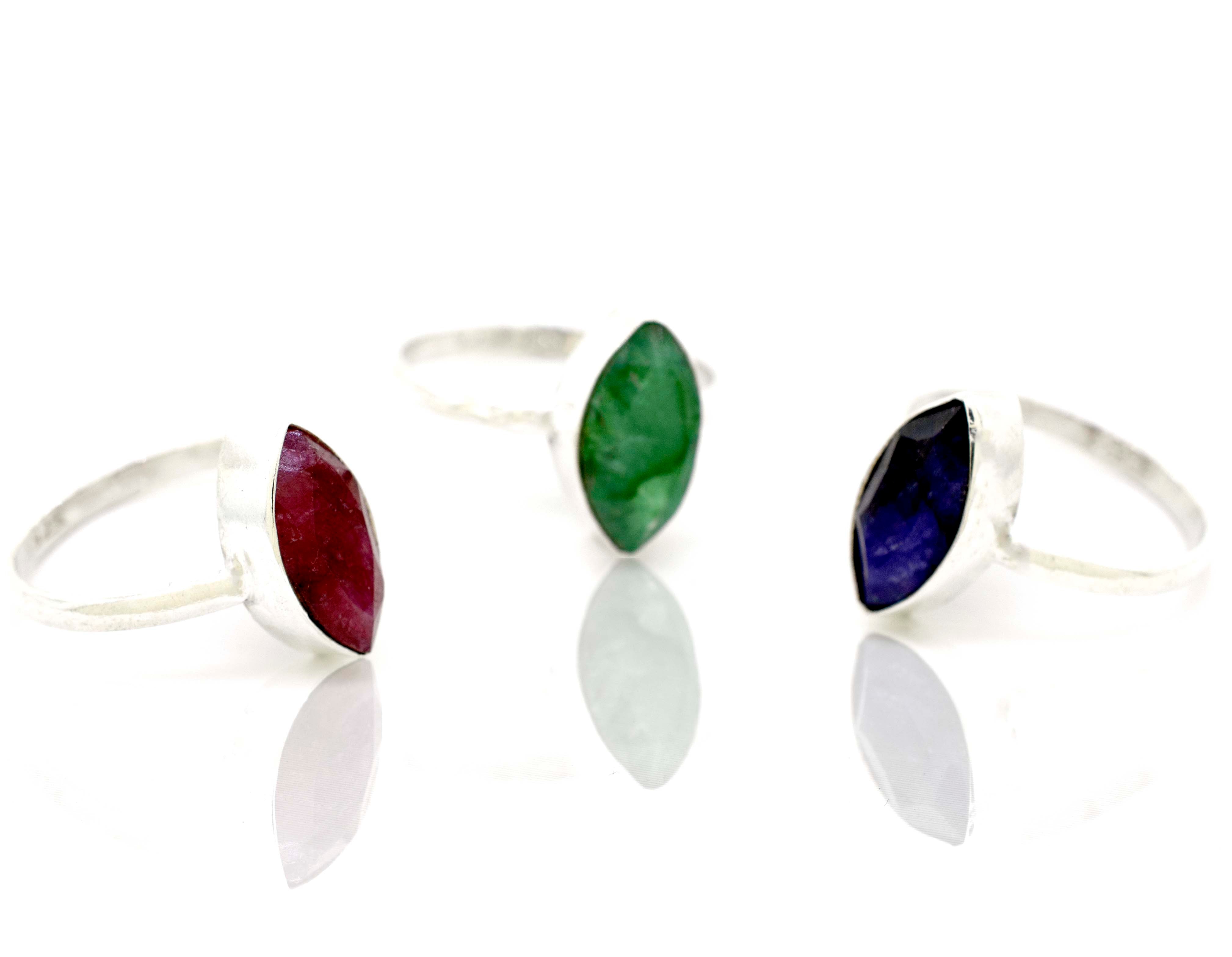 Three Simple Marquise Shaped Gemstone Rings with different colored stones on a white surface.