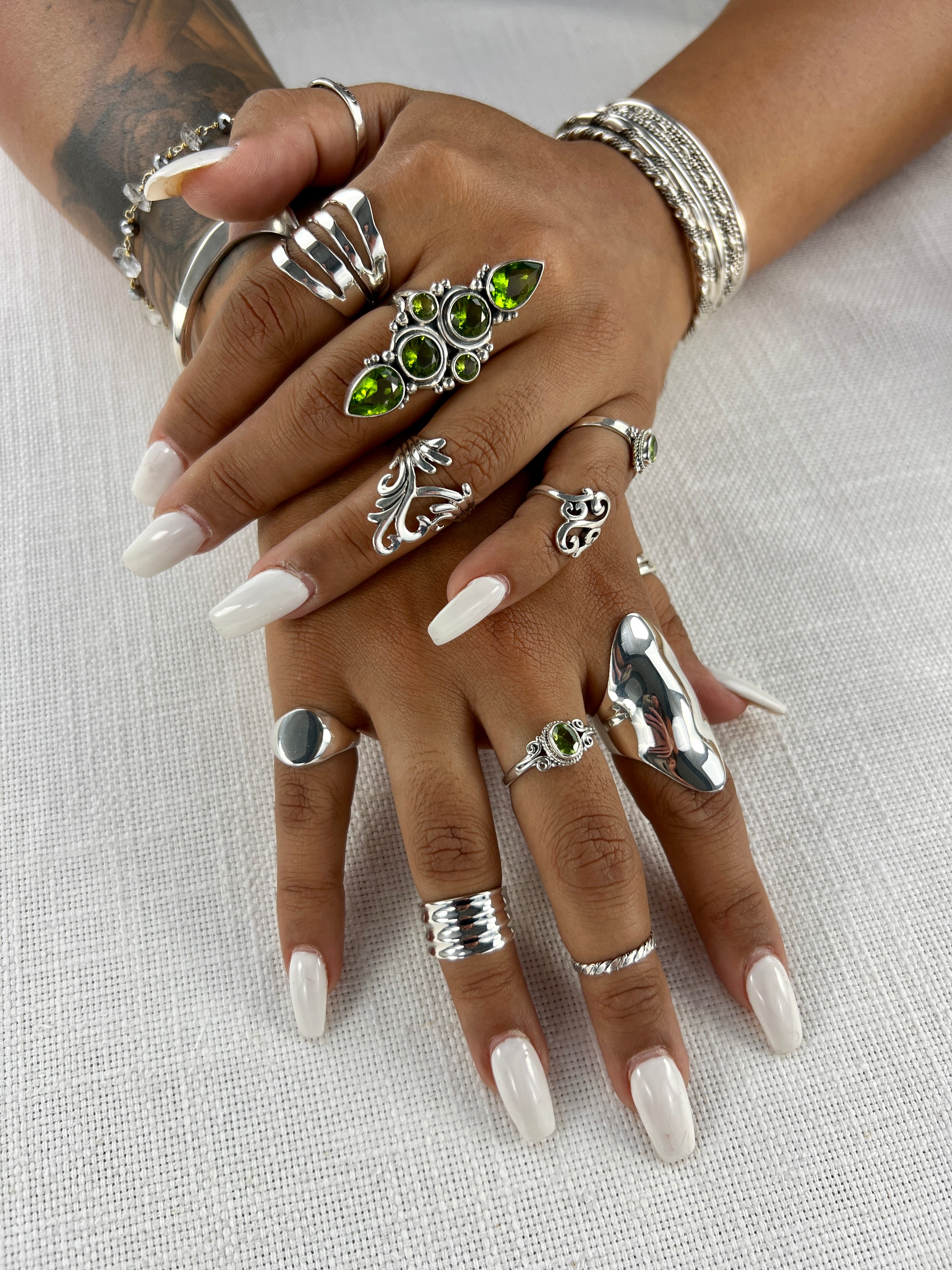 A woman's hands adorned with a beautiful Exquisite Peridot Statement Ring and a stunning silver ring.