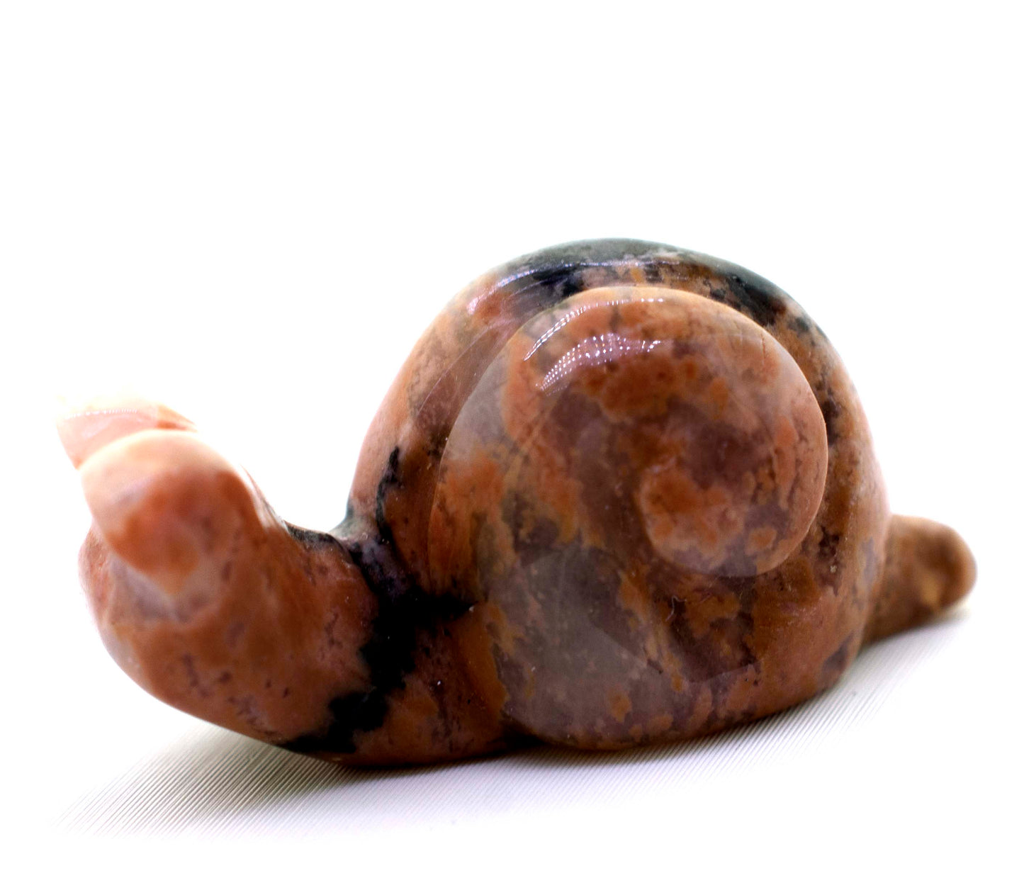 A small Snail Carved Gemstone Figure on a white surface.