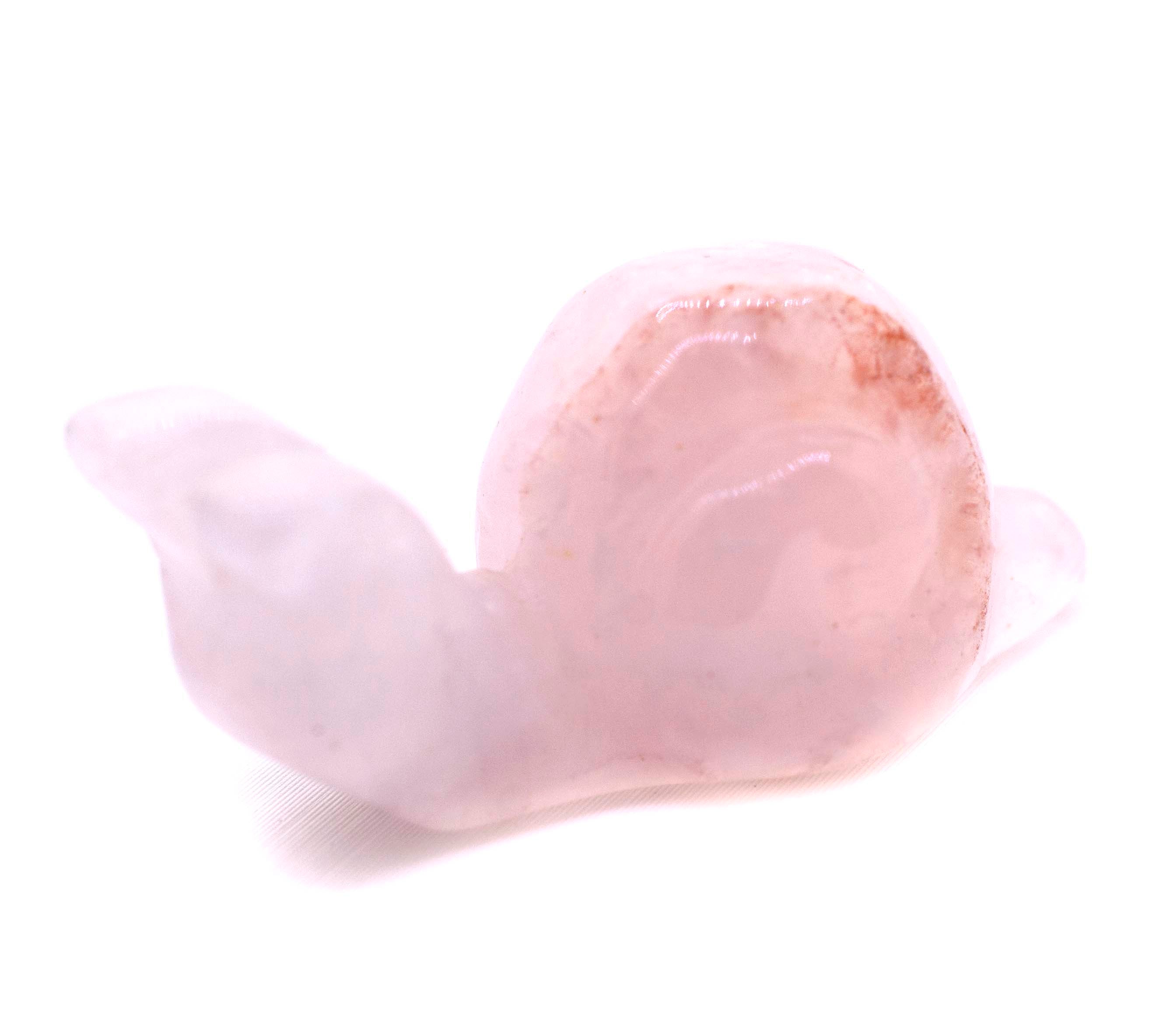 A small pink Snail Carved Gemstone Figure sitting on a white surface, perfect as a decor accent.