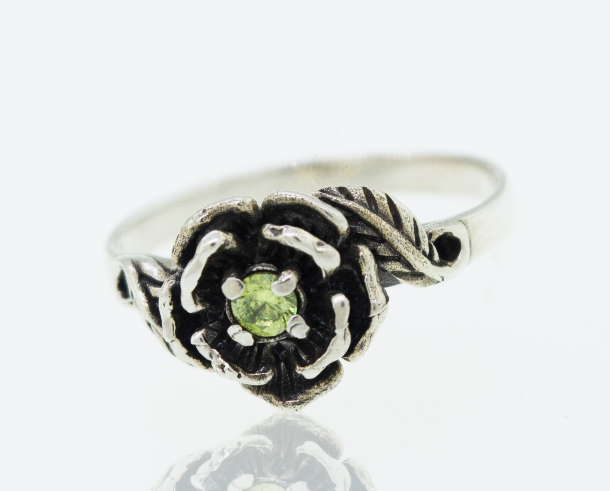Rose Ring With Cubic Zirconia Stone featuring a flower design with a small green gemstone at the center.