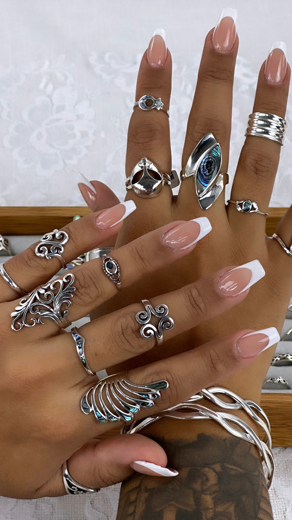 A hand adorned with many Beautiful Inlay Stone Wing Fan Rings, shimmering with enchanting treasures.