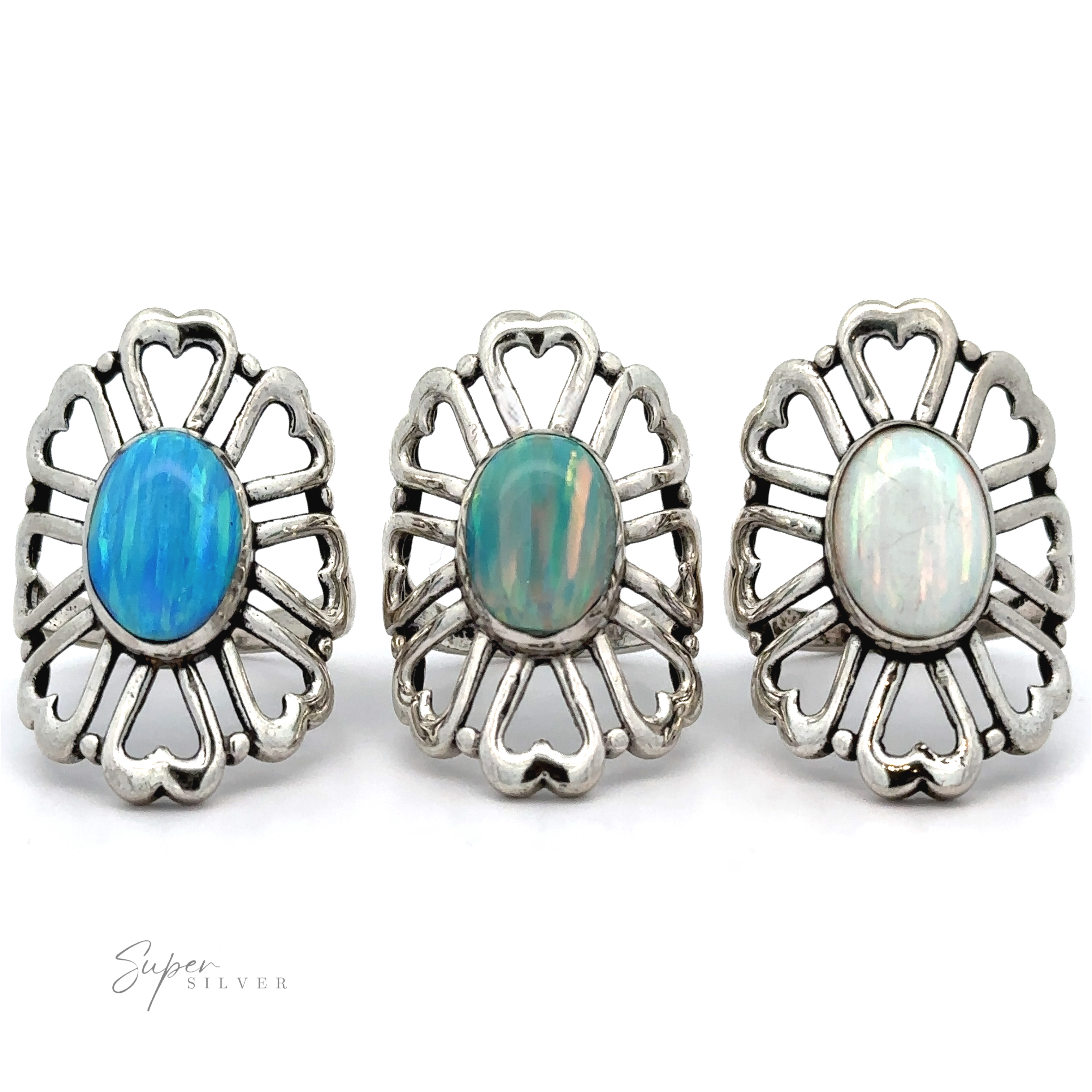 Three American Made Opal Flower Rings with Heart Shaped Petals featuring blue and green opals are displayed in a row against a white background. Handcrafted in America, these exquisite pieces showcase artisanal craftsmanship.