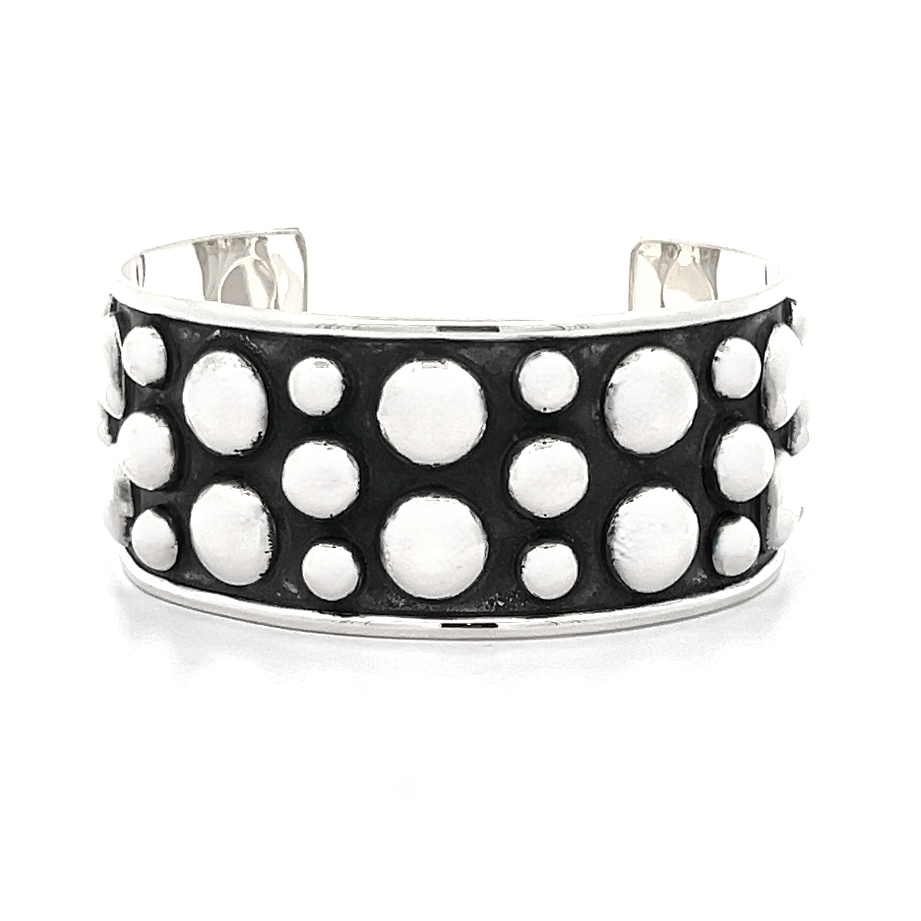 The Unique Ball Studded Cuff is a silver bracelet with a black background, adorned with a bold pattern of white circular designs, making it the perfect statement piece for those with a rebellious vibe.