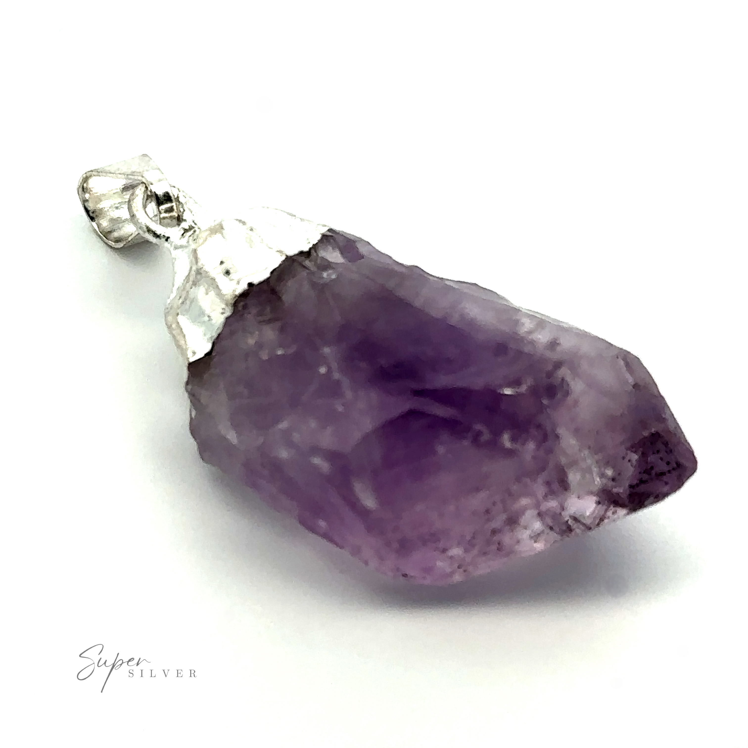 A Raw Crystal Pendant With Silver Cap features a purple, translucent stone set in silver with an irregular, rough cut and a smooth silver bail for attaching to a necklace. The raw crystal showcases visible facets and inclusions.