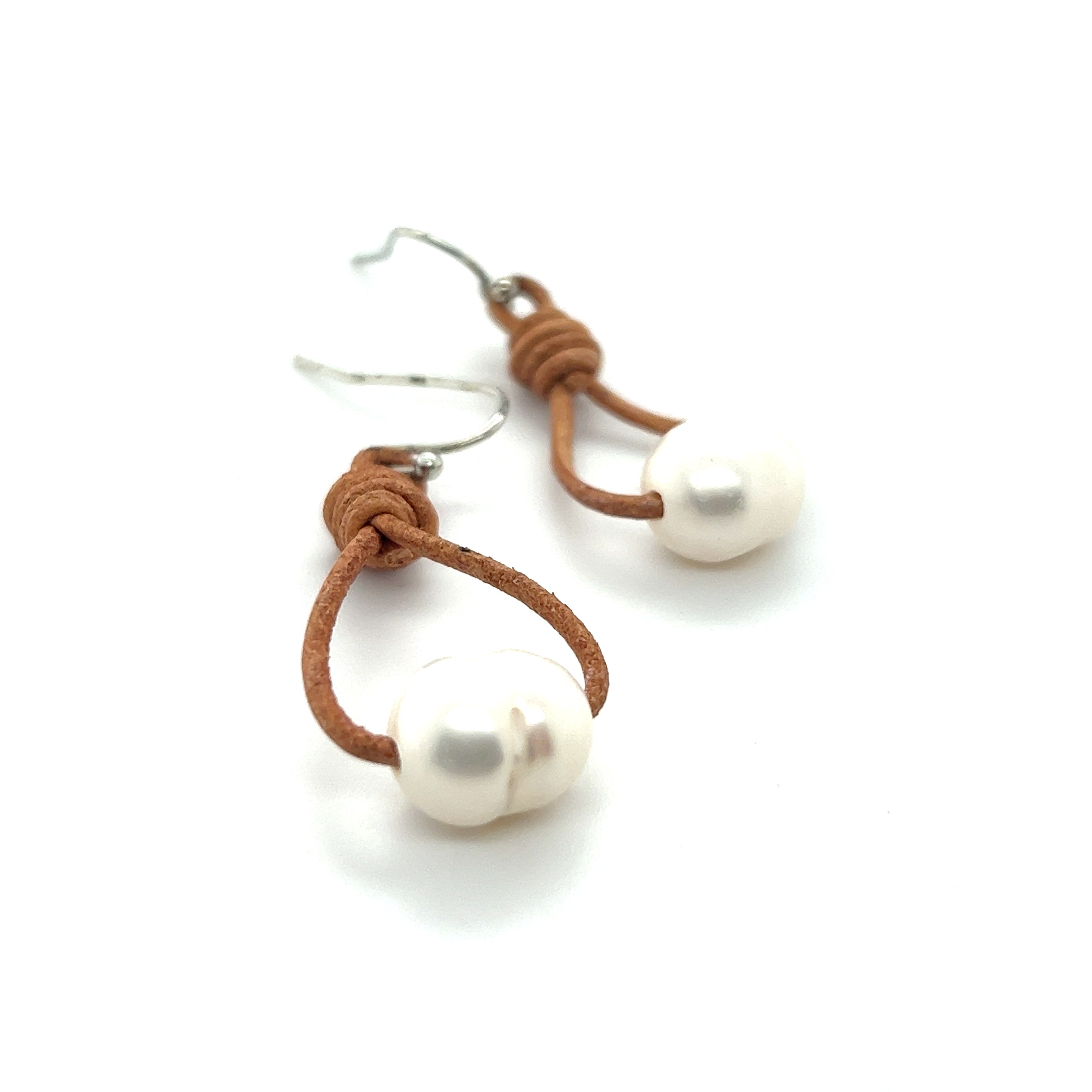 A pair of Super Silver's Leather Cord and Pearl Earrings, exuding a laid-back style.