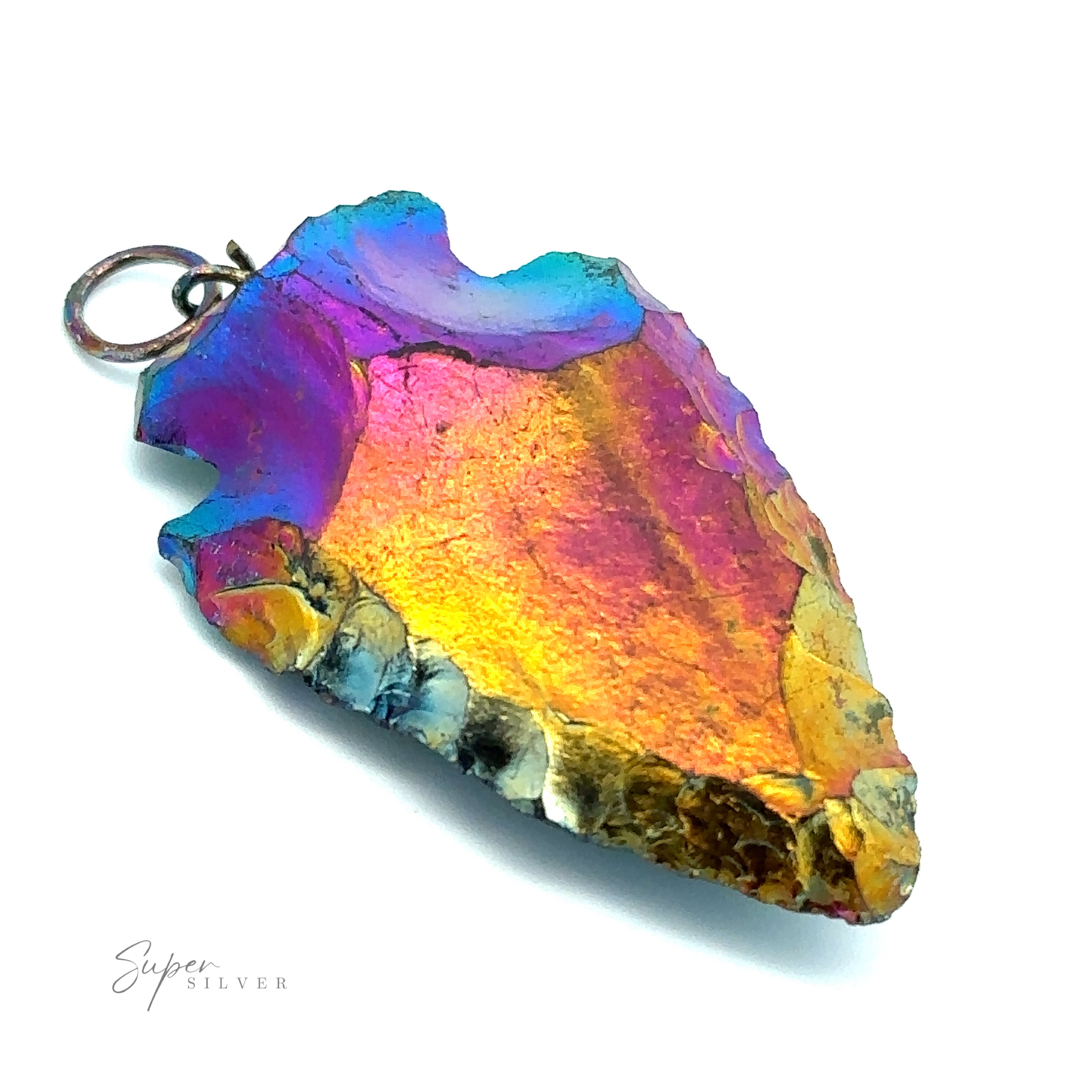 A colorful Rainbow Hematite Arrowhead Pendant with iridescent shades of blue, purple, pink, and gold, attached to a small metal ring crafted from mixed metals, lays elegantly on a white surface.