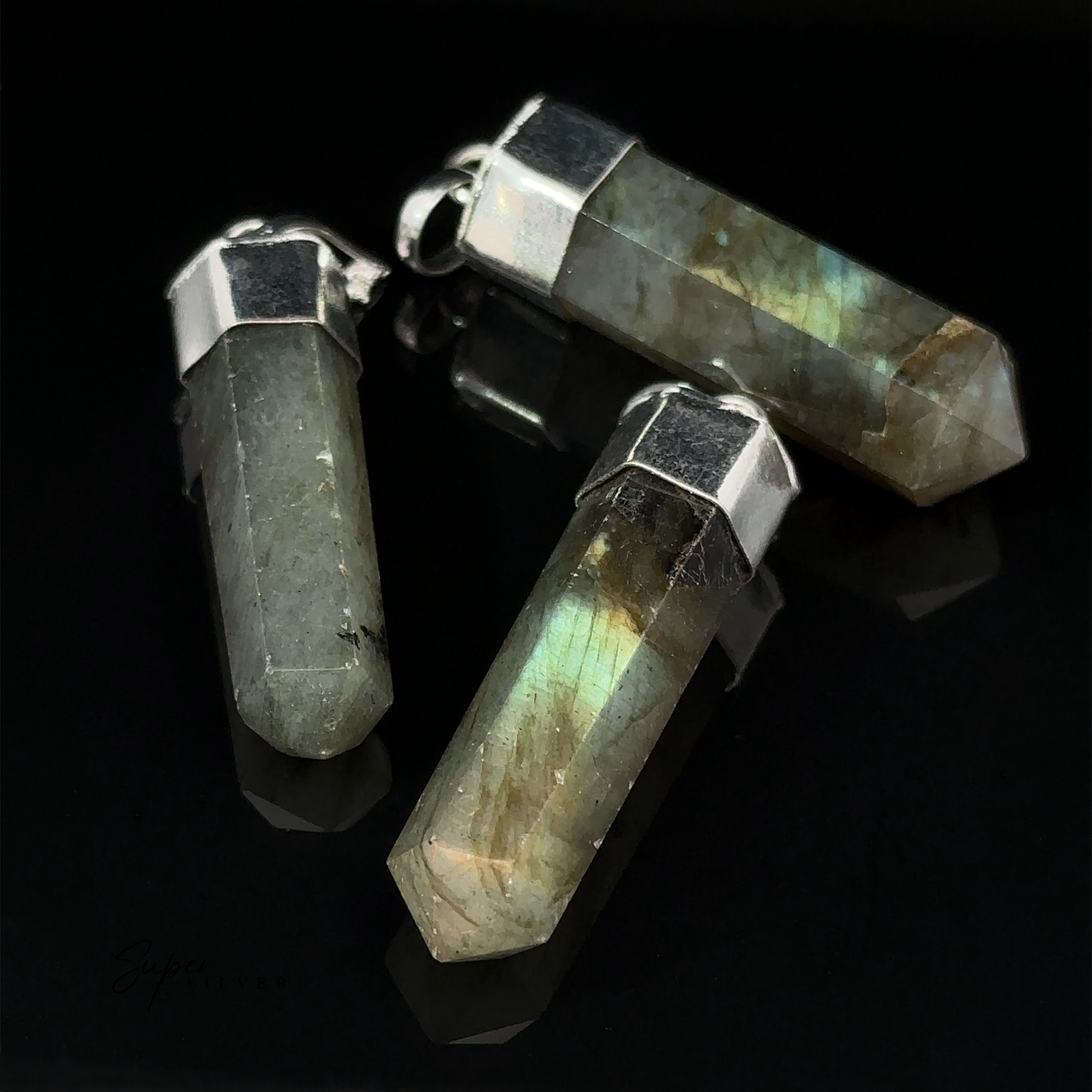 Three Simple Gemstone Point Pendants with silver caps, featuring an earthy design, lay on a black surface.