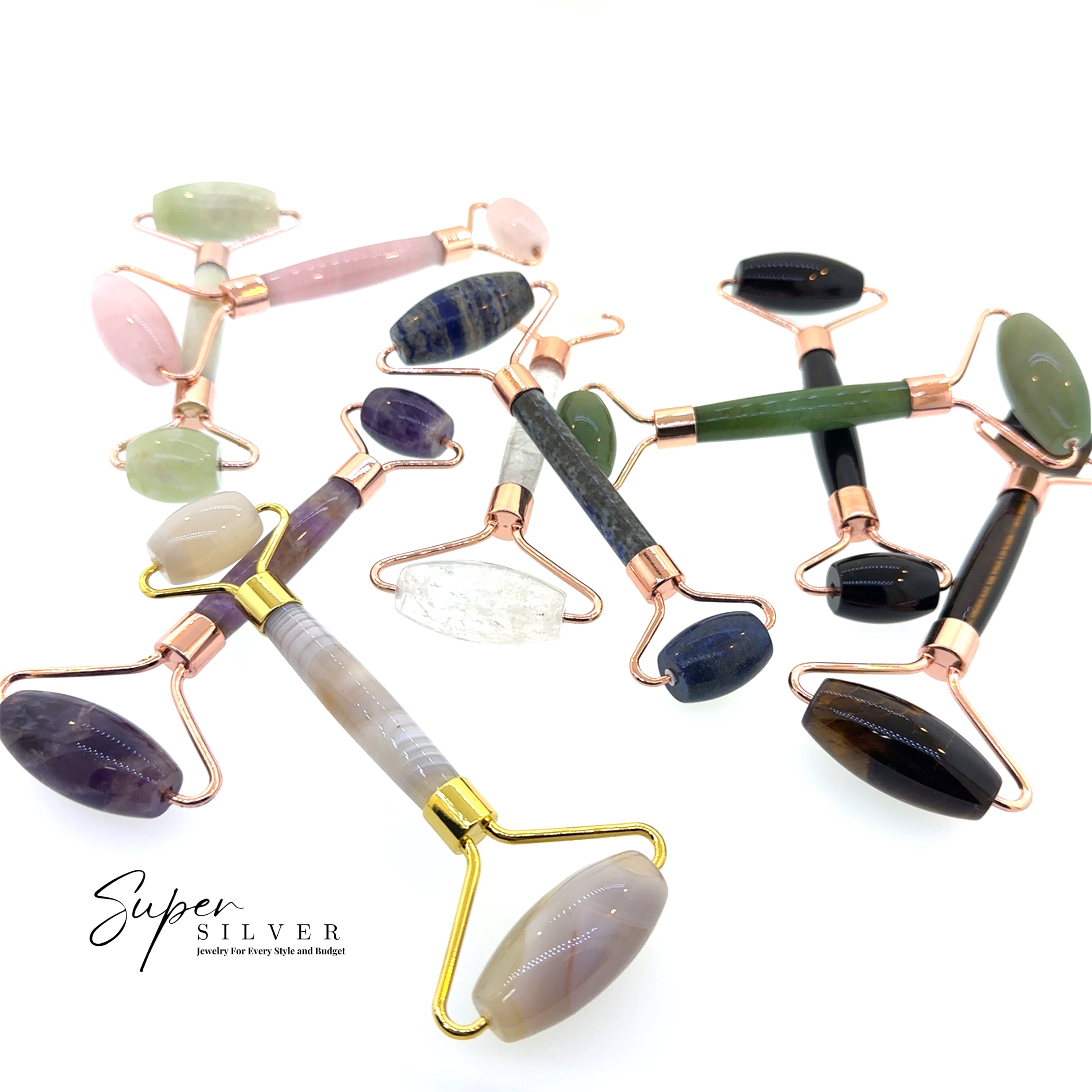 Stone Face-Rollers with gemstone heads and rose gold handles, ideal for skincare routines, are displayed on a white surface. The "Super Silver" logo is visible in the bottom left corner.