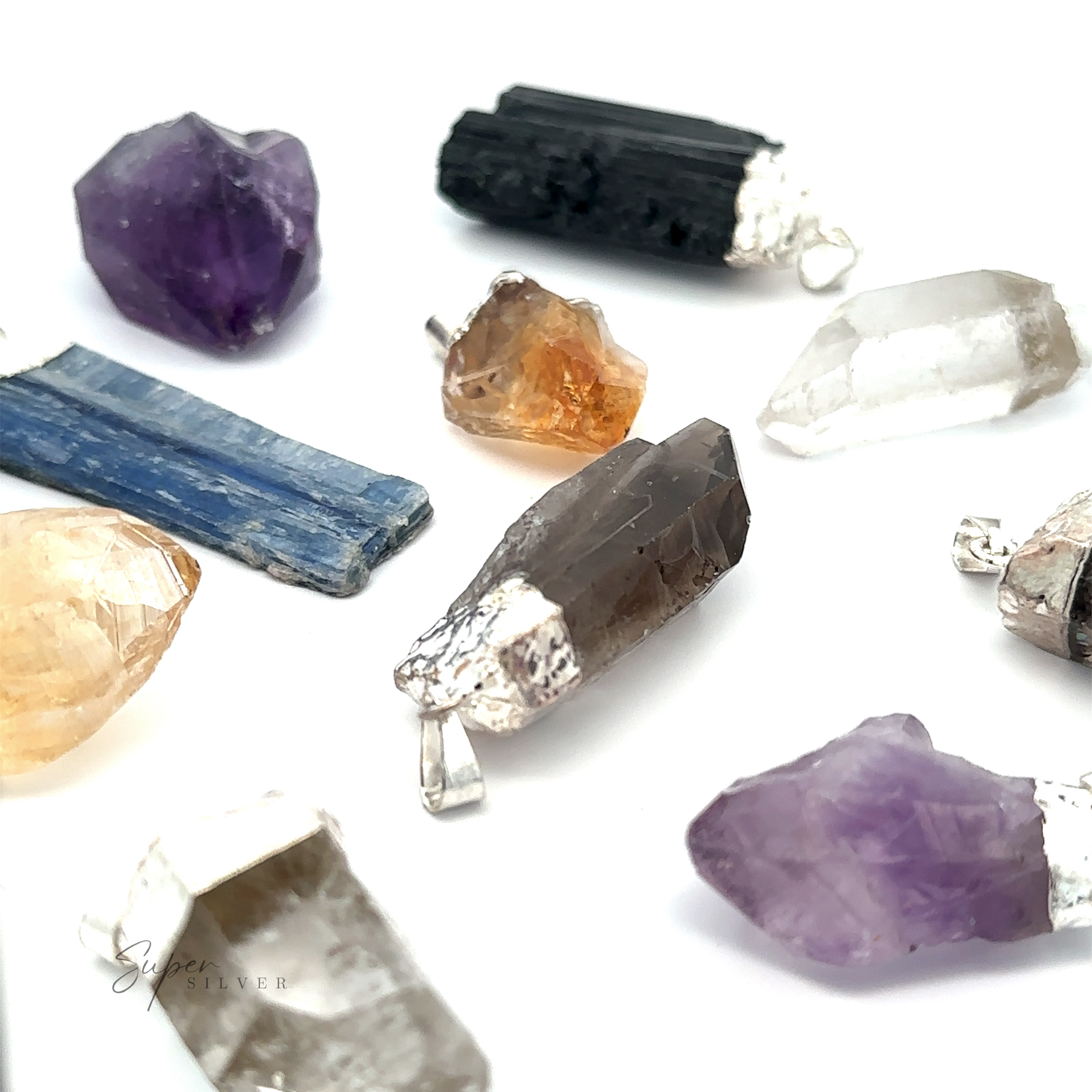 An assortment of Raw Crystal Pendant With Silver Cap, including amethyst, black tourmaline, and kyanite, displayed against a white background. Each raw crystal is capped with silver-colored metal.