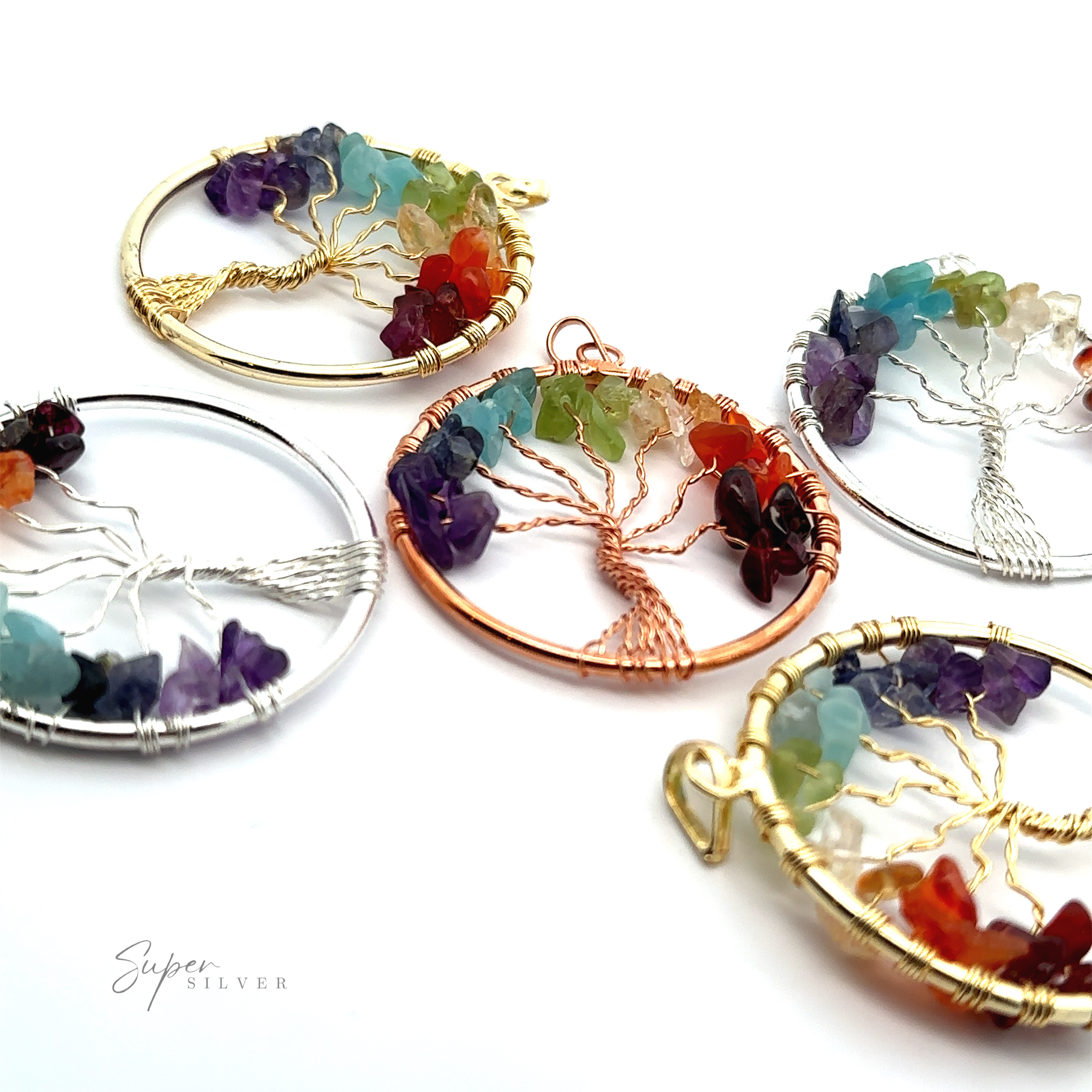 Five Wire-Wrapped Chakra Tree of Life Pendants featuring multicolored chakra stones are displayed on a white surface. The wire-wrapped pendants have circular frames in gold, silver, and copper tones.