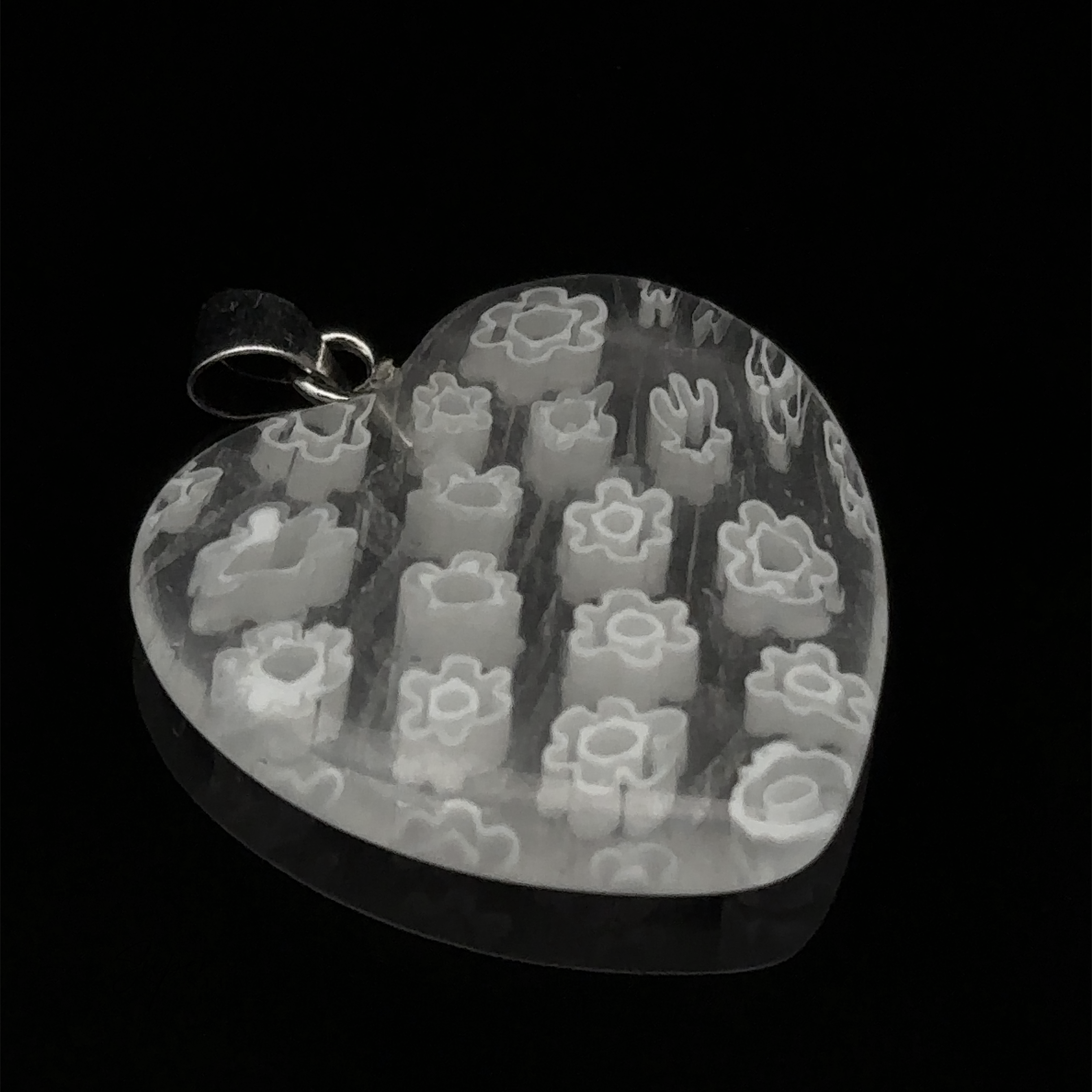 A Heart Pendant with Flower Pattern featuring delicate white geometric and floral patterns inside, set against a striking black background.