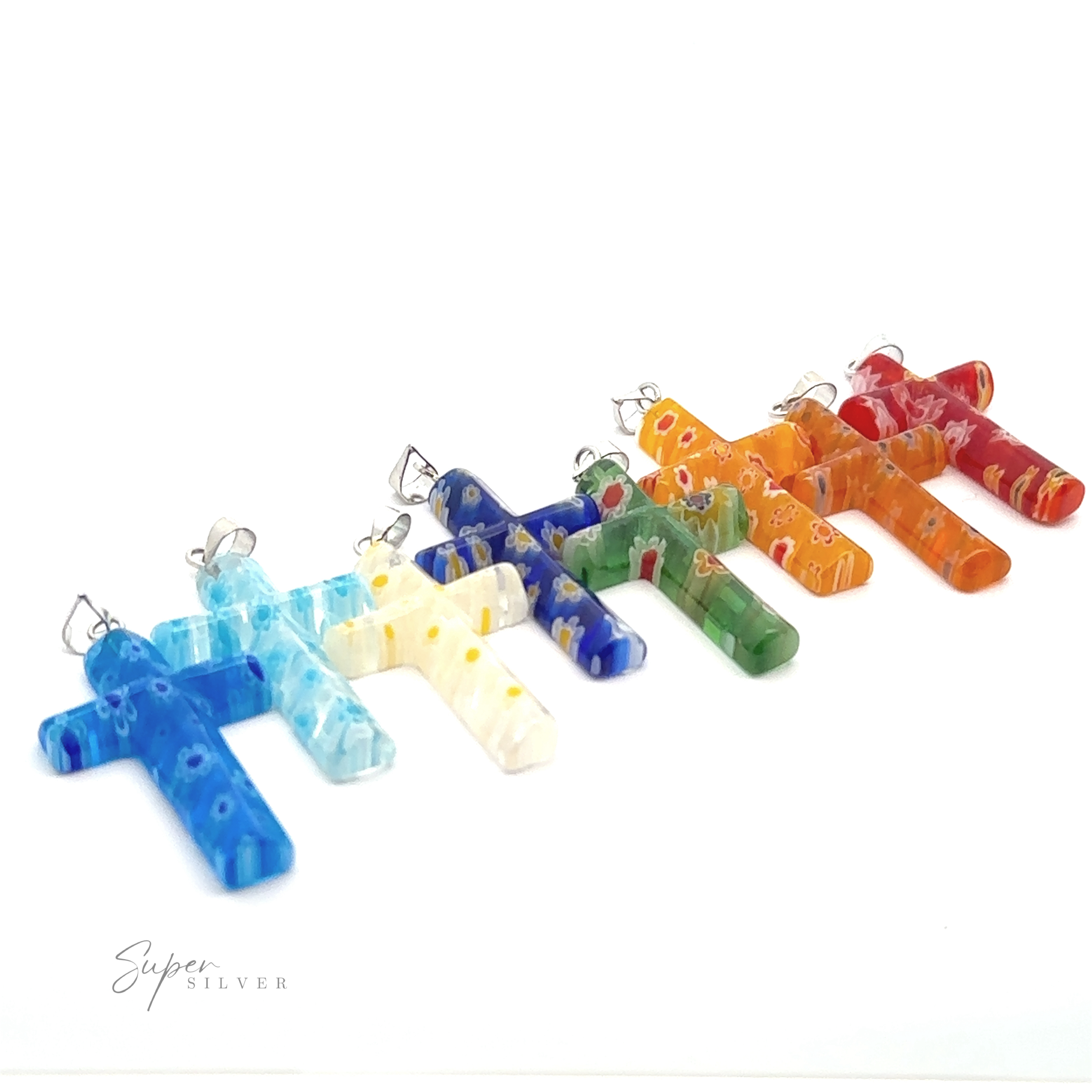 A row of seven colorful **Cross Pendants with Flower Pattern** made from translucent resin with silver loops against a white background. The pendants, in light blue, yellow, dark blue, green, orange, and red, feature a delicate flower pattern.