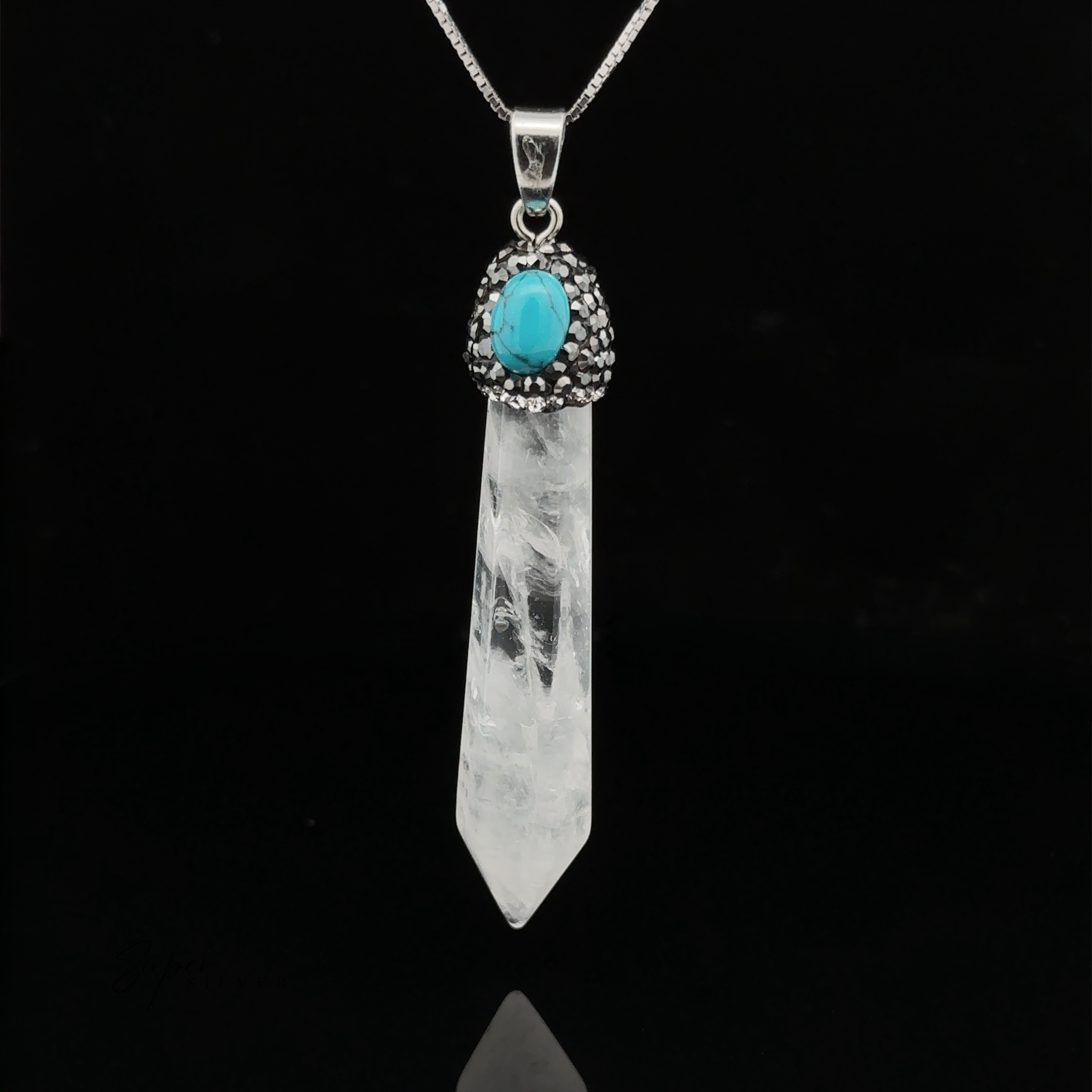 A pendant necklace featuring a clear quartz Stone Obelisk Pendant attached to a silver chain. The crystal is topped with a turquoise stone encased in a decorative silver setting. Hematite beads adorn the chain, adding an extra touch of elegance.