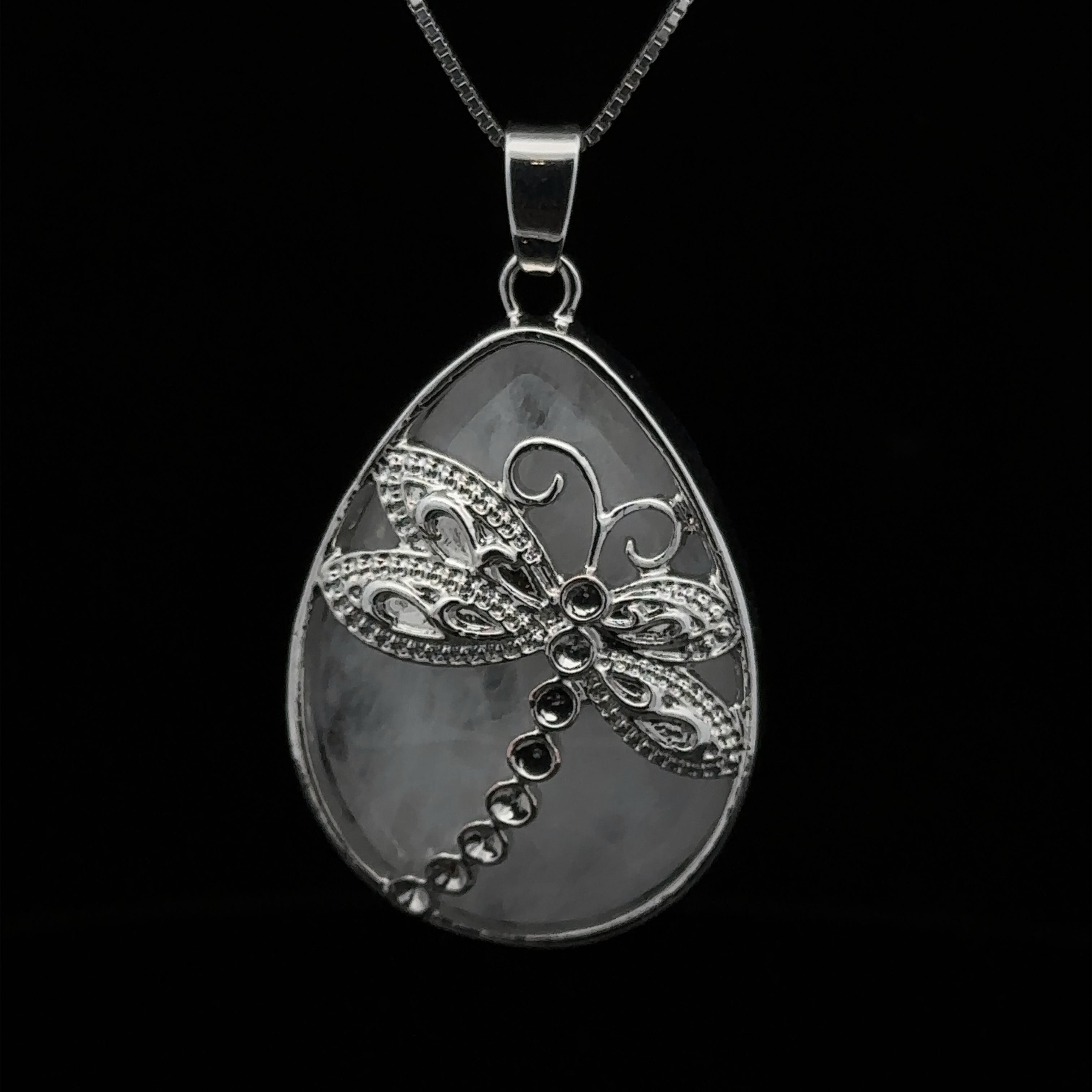 A Teardrop Stone pendant with Dragonfly with a detailed dragonfly design in the center, crafted from mixed metals and adorned with an amethyst stone, hanging from a silver chain, set against a black background.