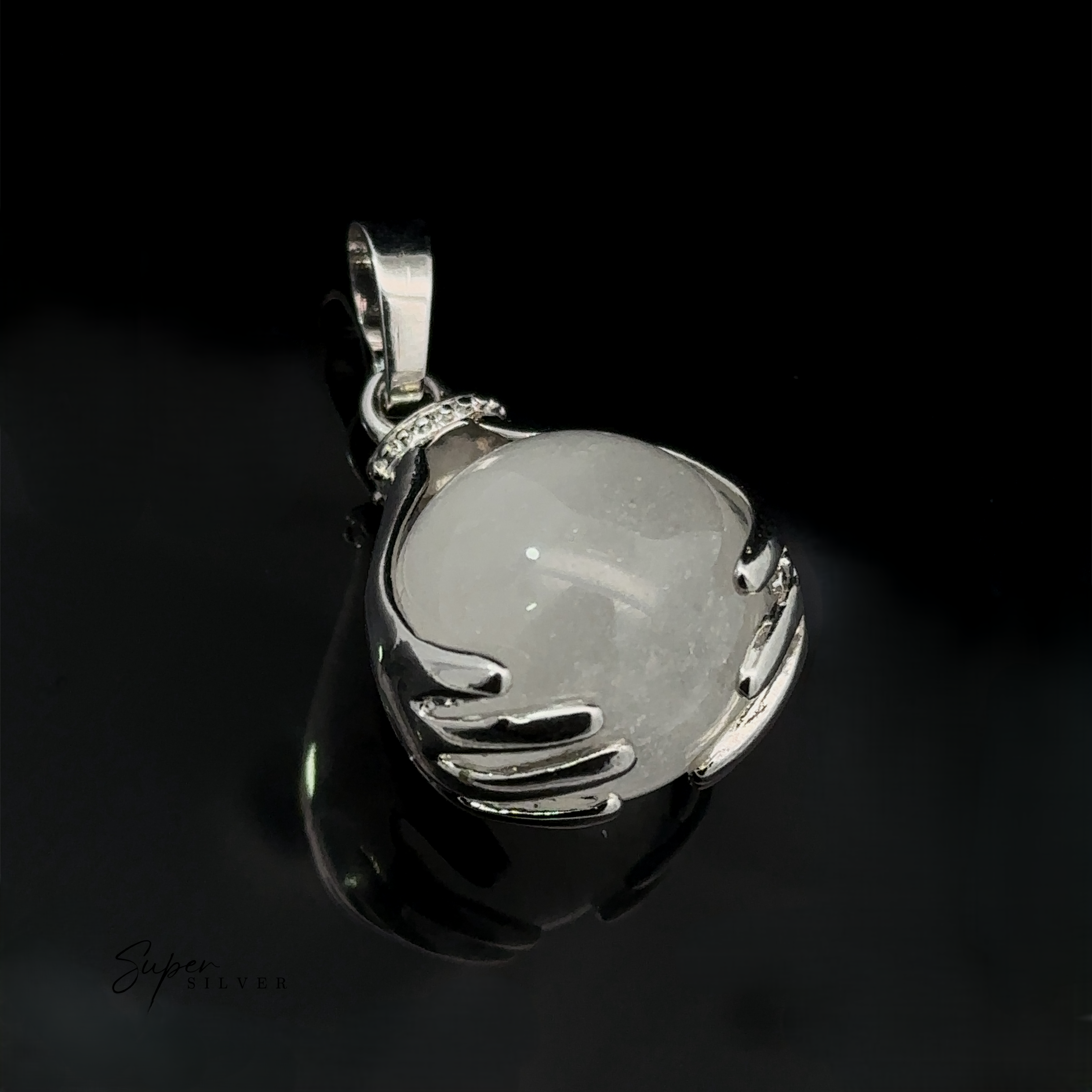 A Sphere Crystal Pendant with a quartz crystal ball held by two sculpted hands, set against a glossy black background. The word "Super Silver" is faintly visible at the bottom left.