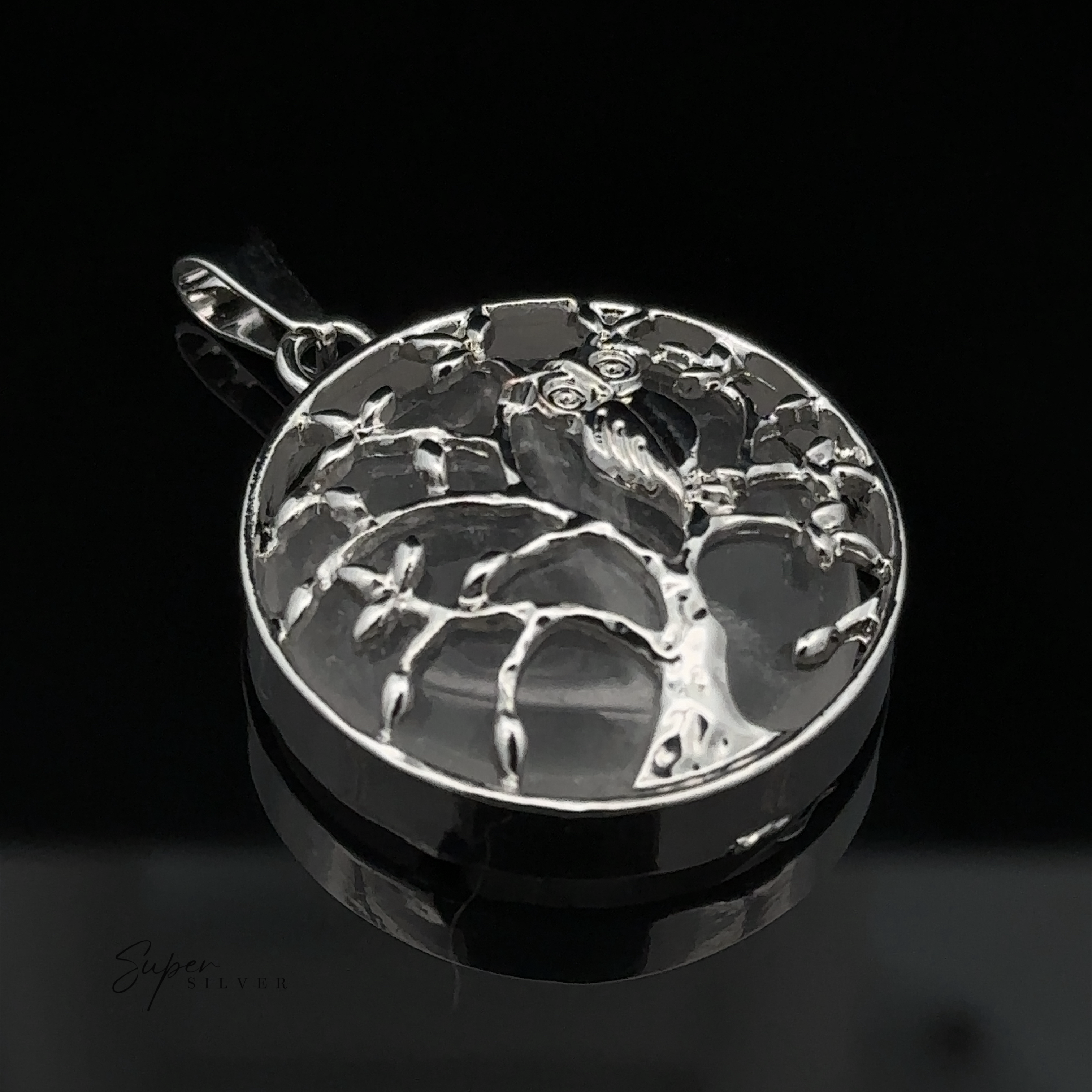 A silver pendant featuring a tree with branches forming a circular frame, set against a black background, beautifully accented with amethyst stones. This Owl and Tree Pendant exudes elegance and charm.