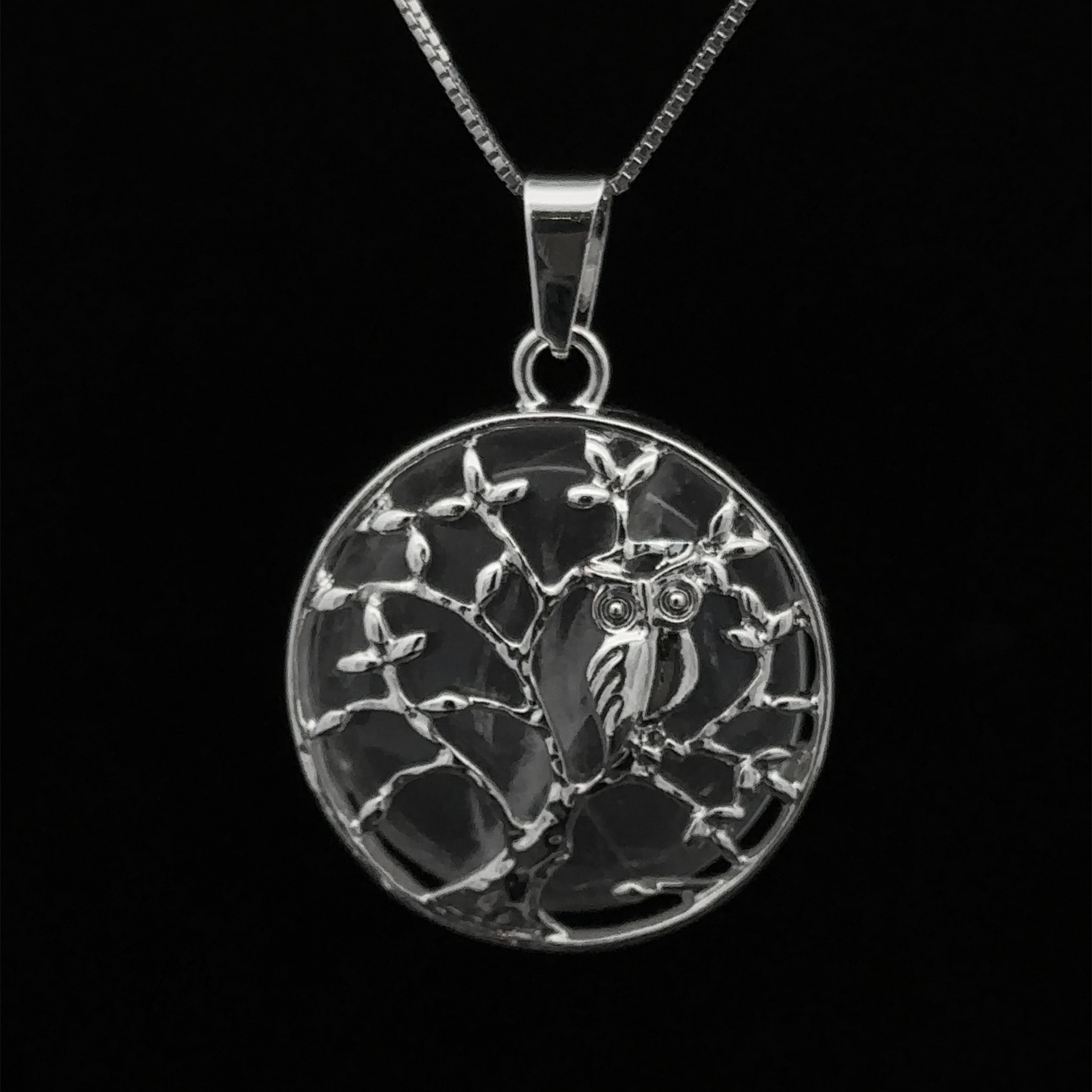Owl and Tree Pendant featuring an owl perched on a tree branch, with detailed carvings against a black background and an amethyst accent.