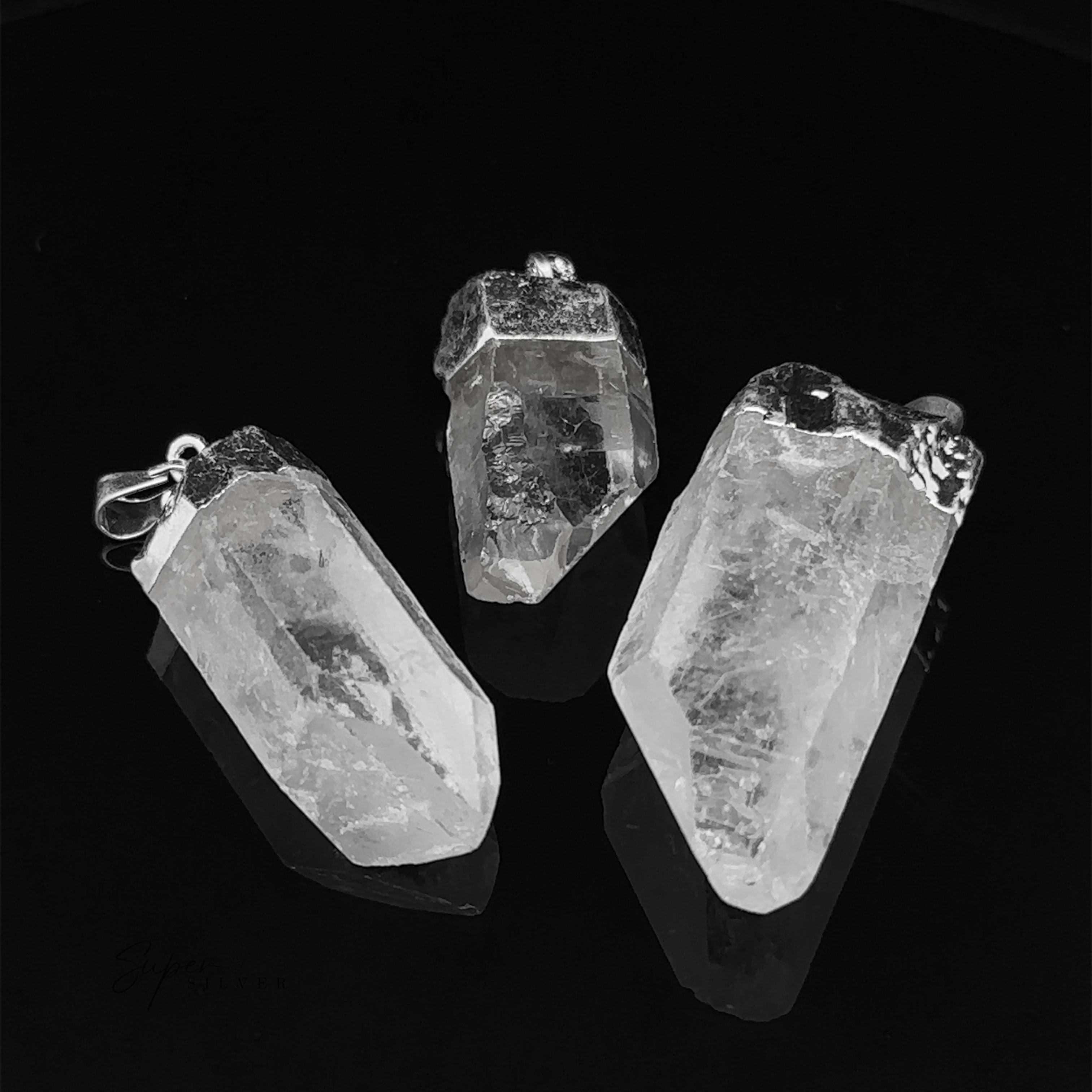Three Raw Crystal Pendants With Silver Caps are elegantly placed on a black surface.