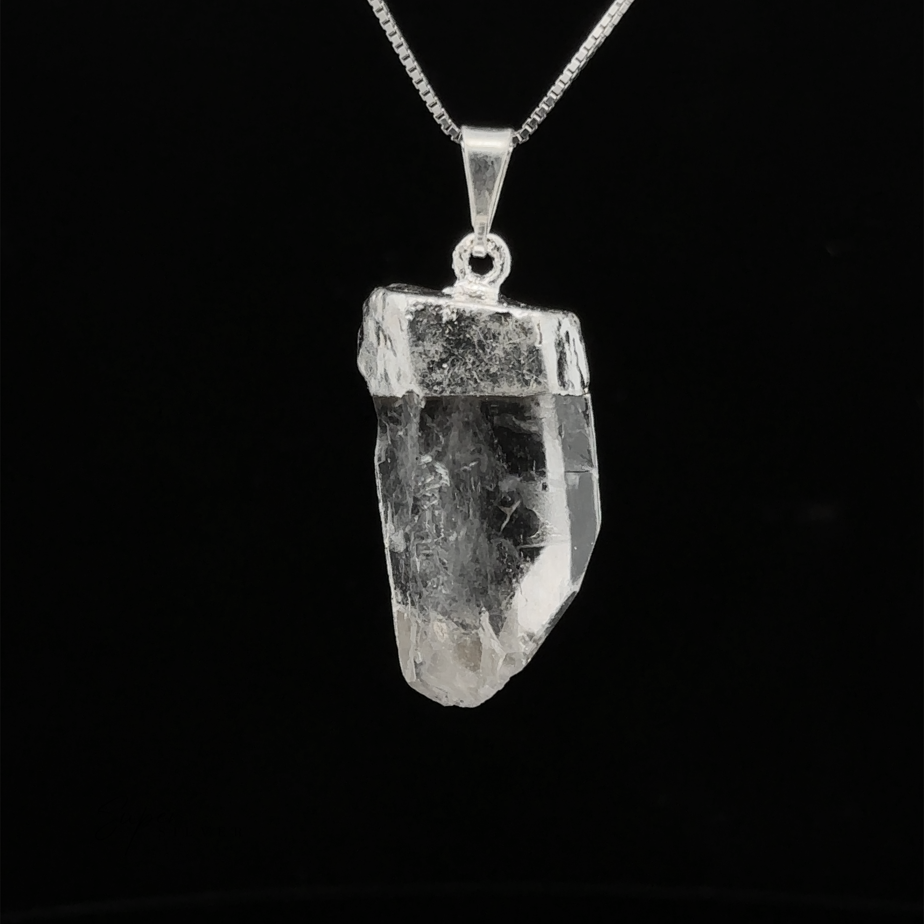 A Raw Crystal Pendant With Silver Cap on a silver chain against a black background. This natural gemstone pendant captures the essence of untouched beauty and mystique.