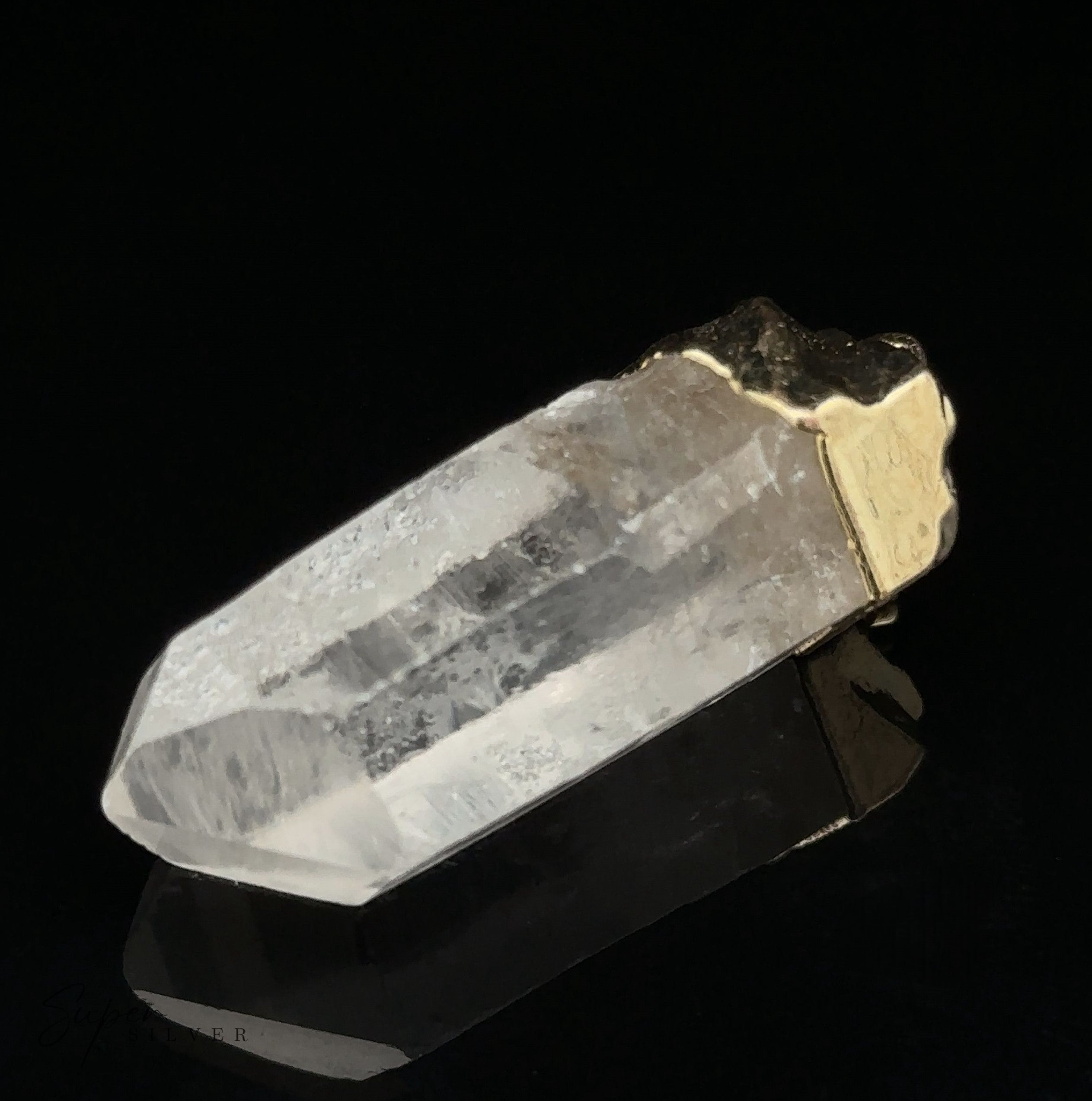 A close-up of a clear quartz crystal with a gold-plated cap on one end, displayed against a black background. This Raw Crystal Pendant With Gold Cap, transformed into a stunning natural gemstone pendant, exudes elegance and simplicity.