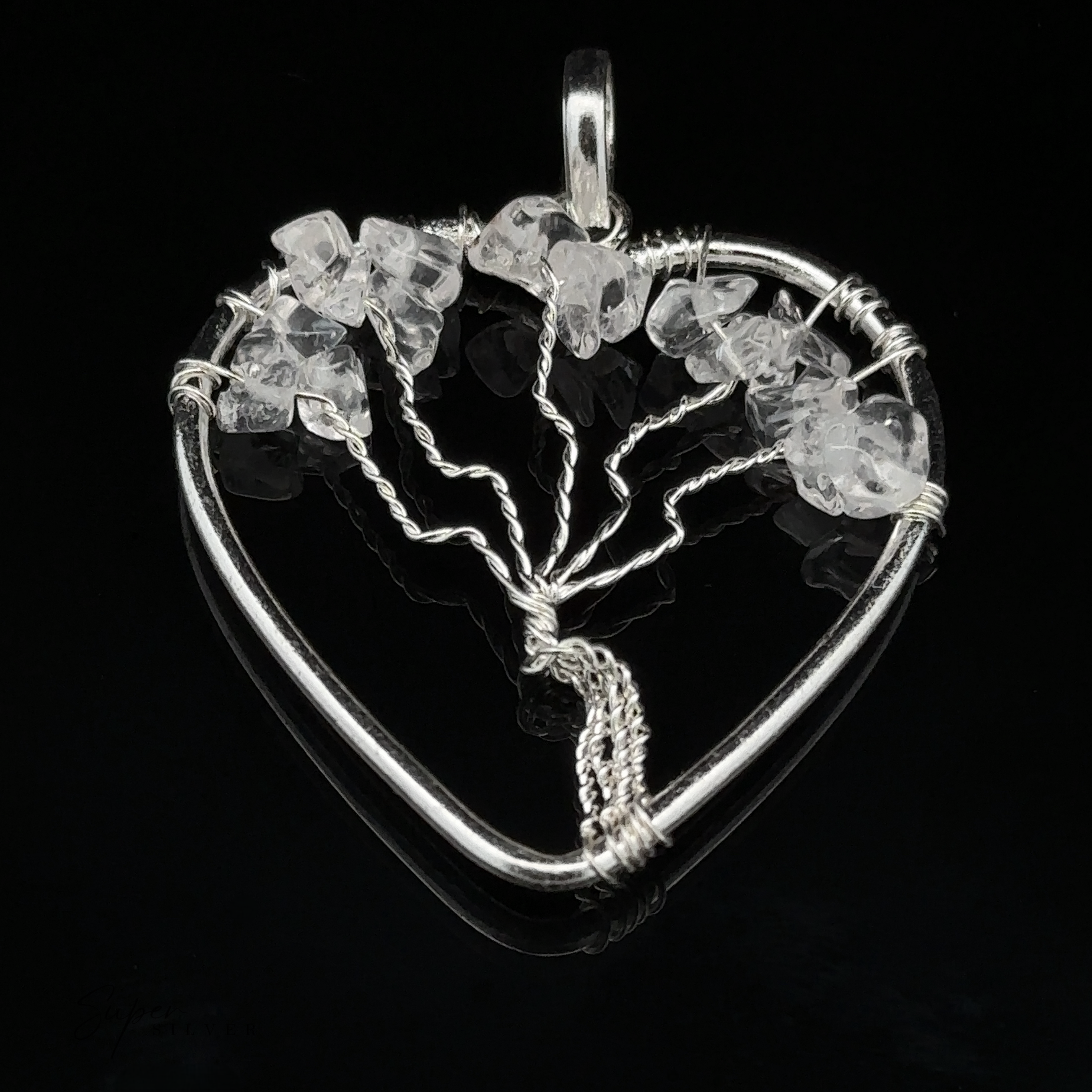 A Heart Shaped Tree of Life Pendant featuring a wire-wrapped design adorned with small clear crystal stones against a black background.
