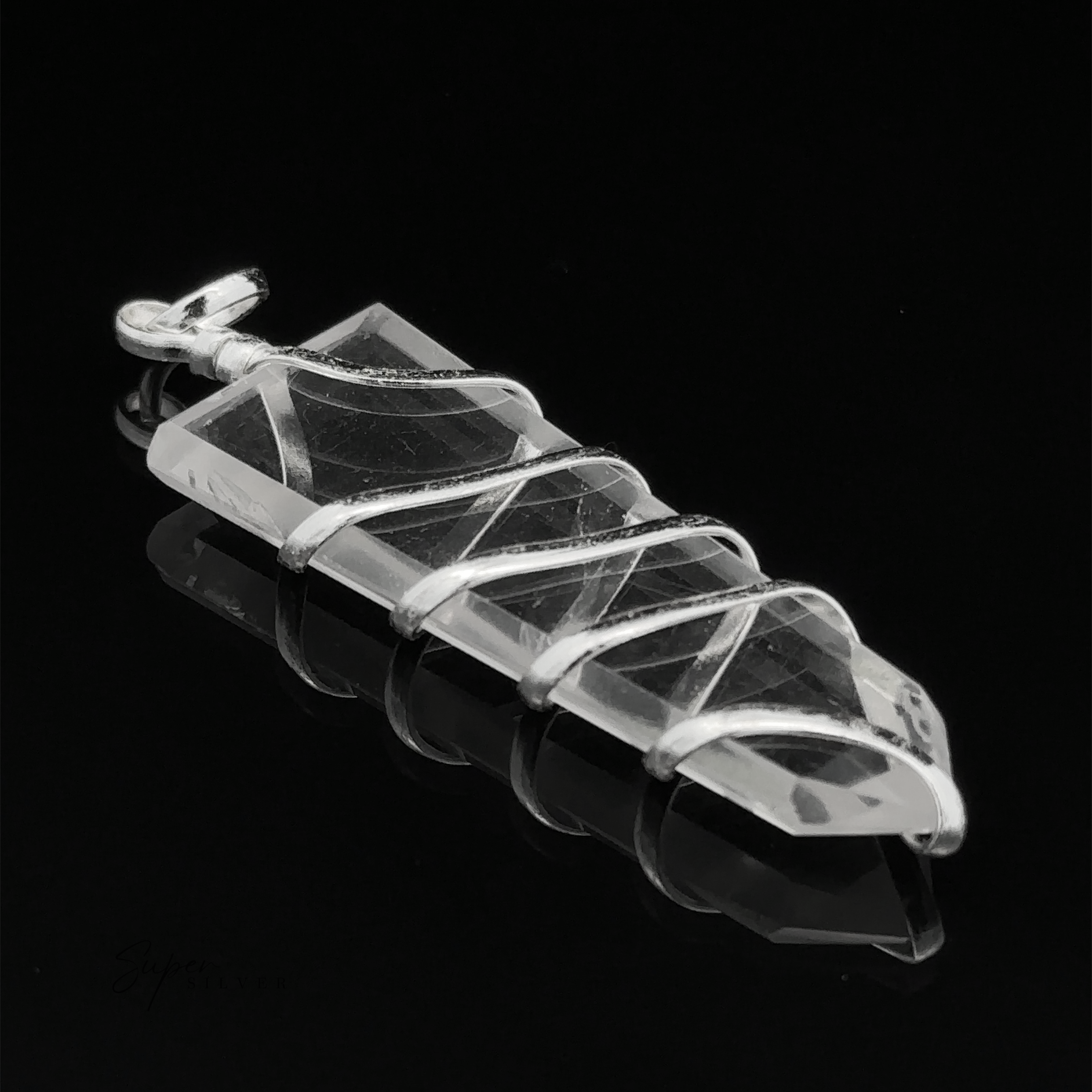 A Wire Wrapped Slab Pendant is showcased on a reflective black surface, its intricate silver wire wrapping highlighting its elegance.