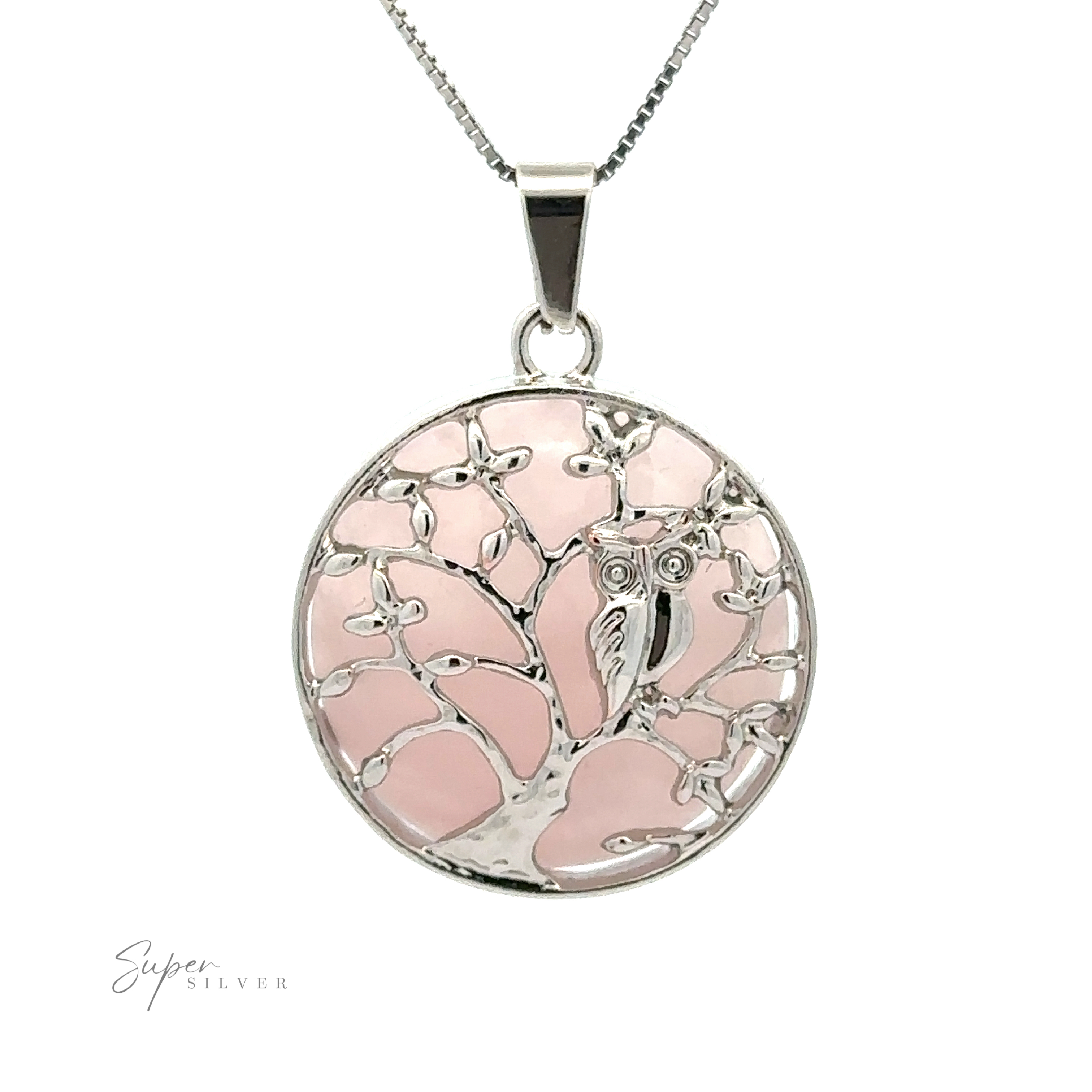 A silver Owl and Tree Pendant featuring a stone tree design with an owl perched on a branch. The background is a pale pink color, highlighting the elegant detail of the mixed metals.
