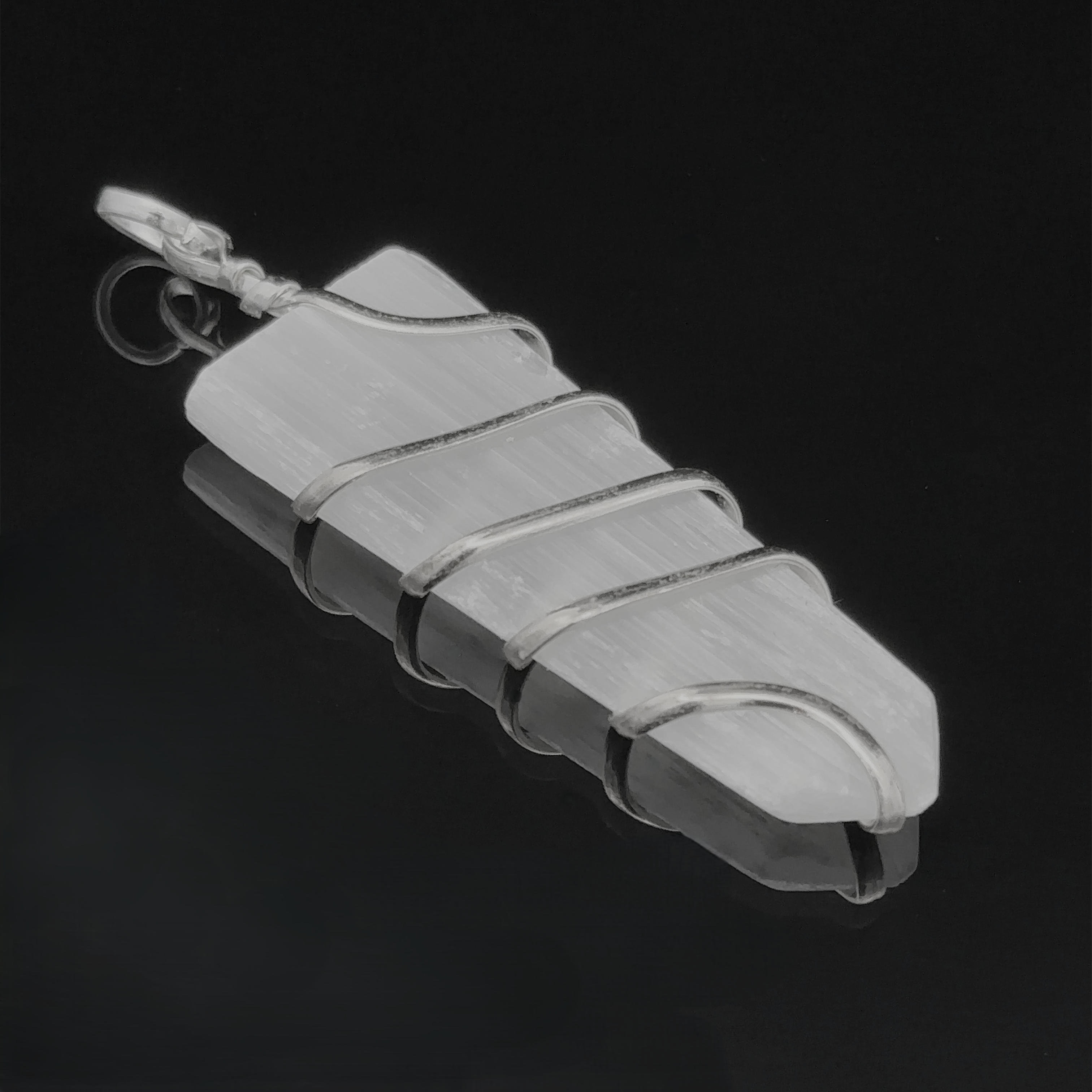 A **Wire Wrapped Slab Pendant** is elegantly encased in a silver wire wrapping, forming a delicate spiral around the stone. This stunning piece of gemstone jewelry is set against a black background, highlighting its intricate design.